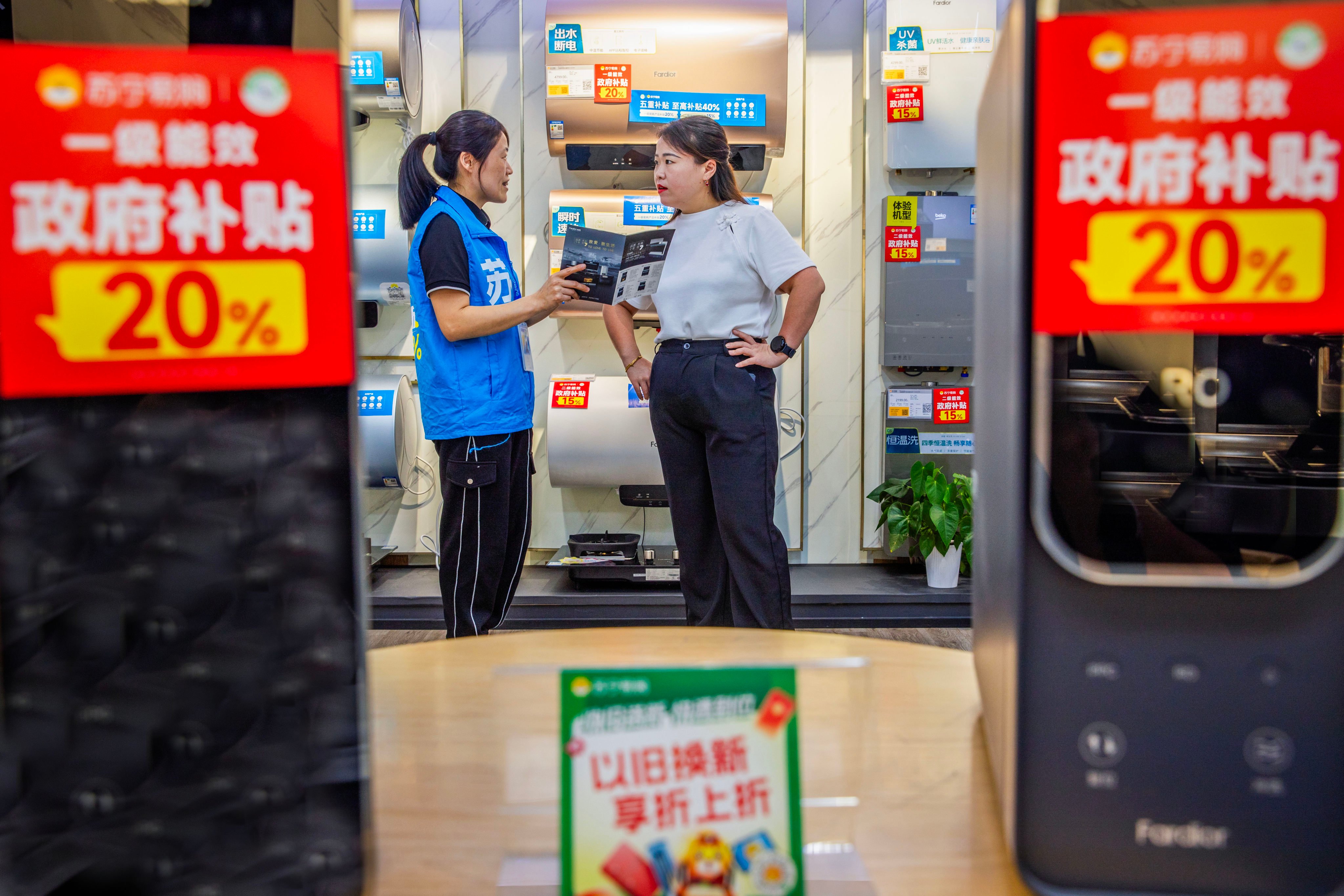 A saleswoman discusses products and government subsidies with a customer in China’s Zhejiang province. Photo: Xinhua
