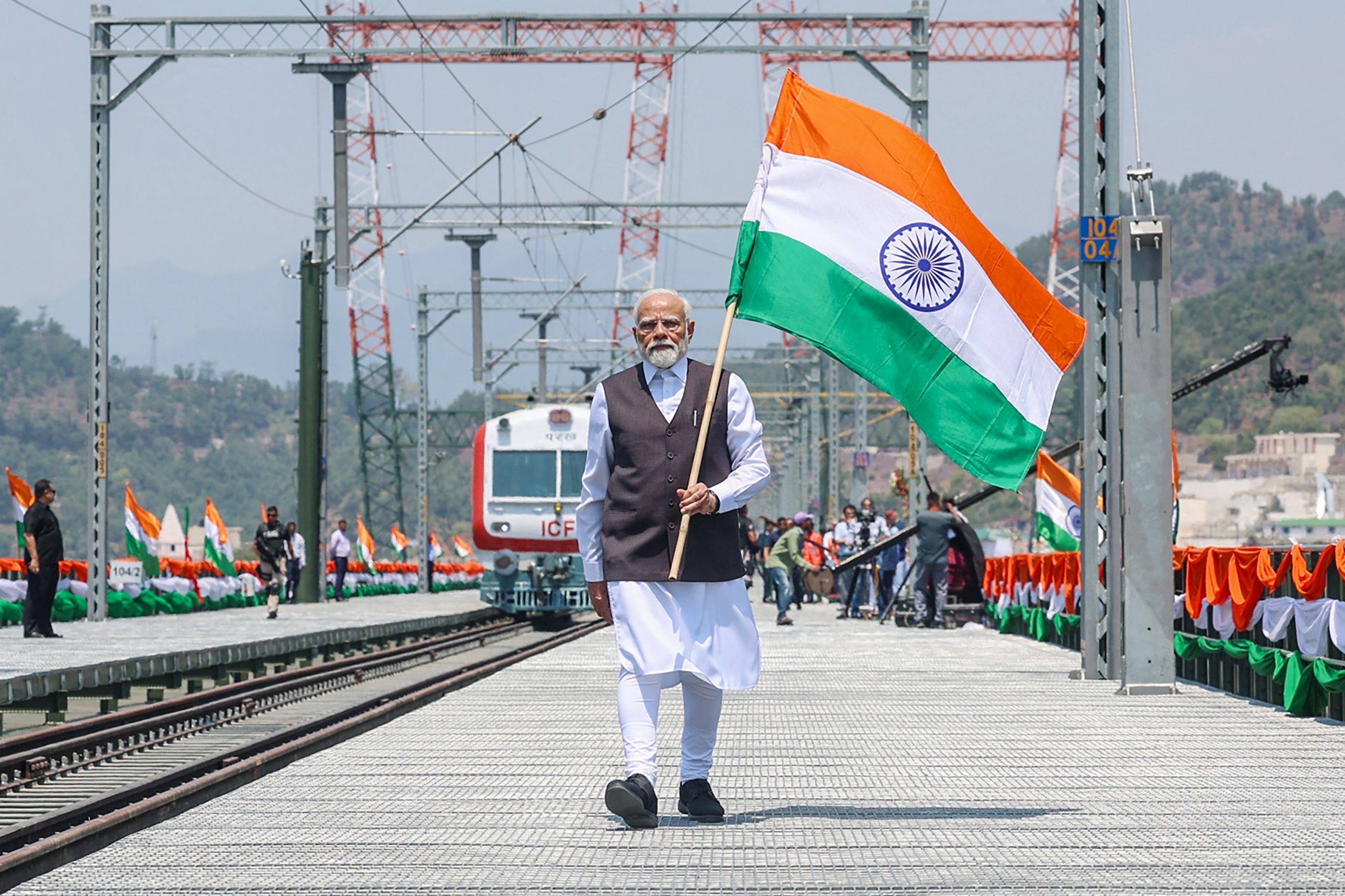 India’s Prime Minister Narendra Modi holds a national flag during the inauguration of a significant new railway bridge on Friday. Photo: Indian Press Information Bureau via AFP
