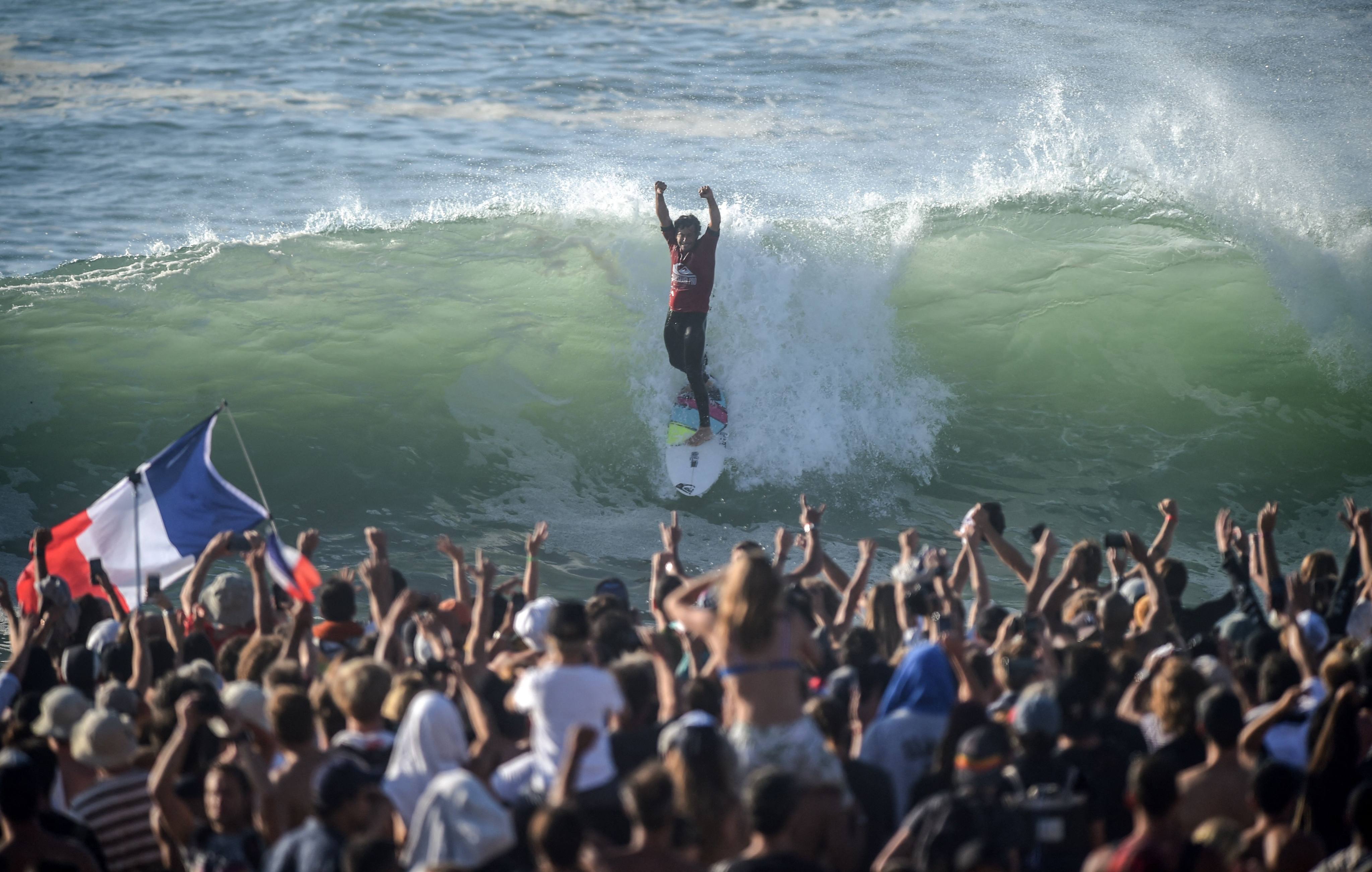 (FILES) French surfer Jeremy Flores raises his arms as he competes in the finals of the men’s championship tour ninth stage of the World Surf League on October 11, 2019 in Capbreton, southwestern France. Europe’s most prized surfer, Jeremy Flores, stepped away from competitive surfing in 2021, only months before a shock tumor diagnosis, which he reveals today in a documentary titled “Dos au mur” (back against the wall). (Photo by GAIZKA IROZ / AFP)