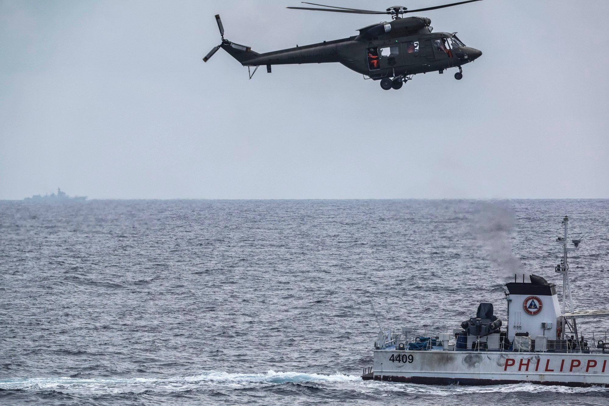 A Chinese naval vessel (behind) moves at a distance from a Philippine coastguard vessel and a Philippine Air Force helicopter in disputed waters of the South China Sea. Photo: EPA-EFE A Chinese naval vessel (behind) moves at a distance from a Philippine coastguard vessel and a Philippine Air Force helicopter in disputed waters of the South China Sea. Photo: EPA-EFE