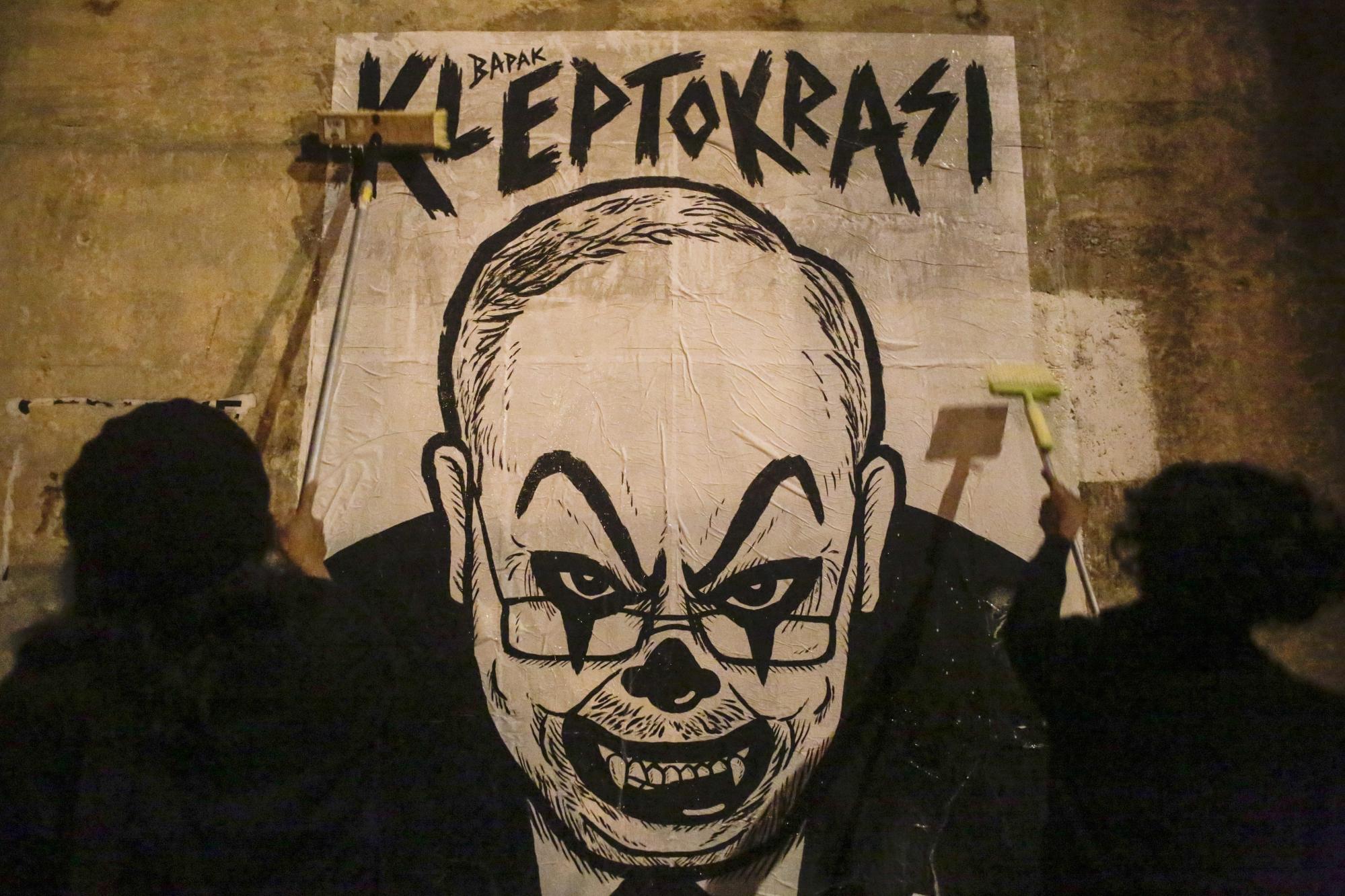 Malaysian cartoonist Fahmi Reza and a friend put up a poster depicting former prime minister Najib Razak with a clown face ahead of a rally in Kuala Lumpur in 2016. Photo: EPA Malaysian cartoonist Fahmi Reza and a friend put up a poster depicting former prime minister Najib Razak with a clown face ahead of a rally in Kuala Lumpur in 2016. Photo: EPA