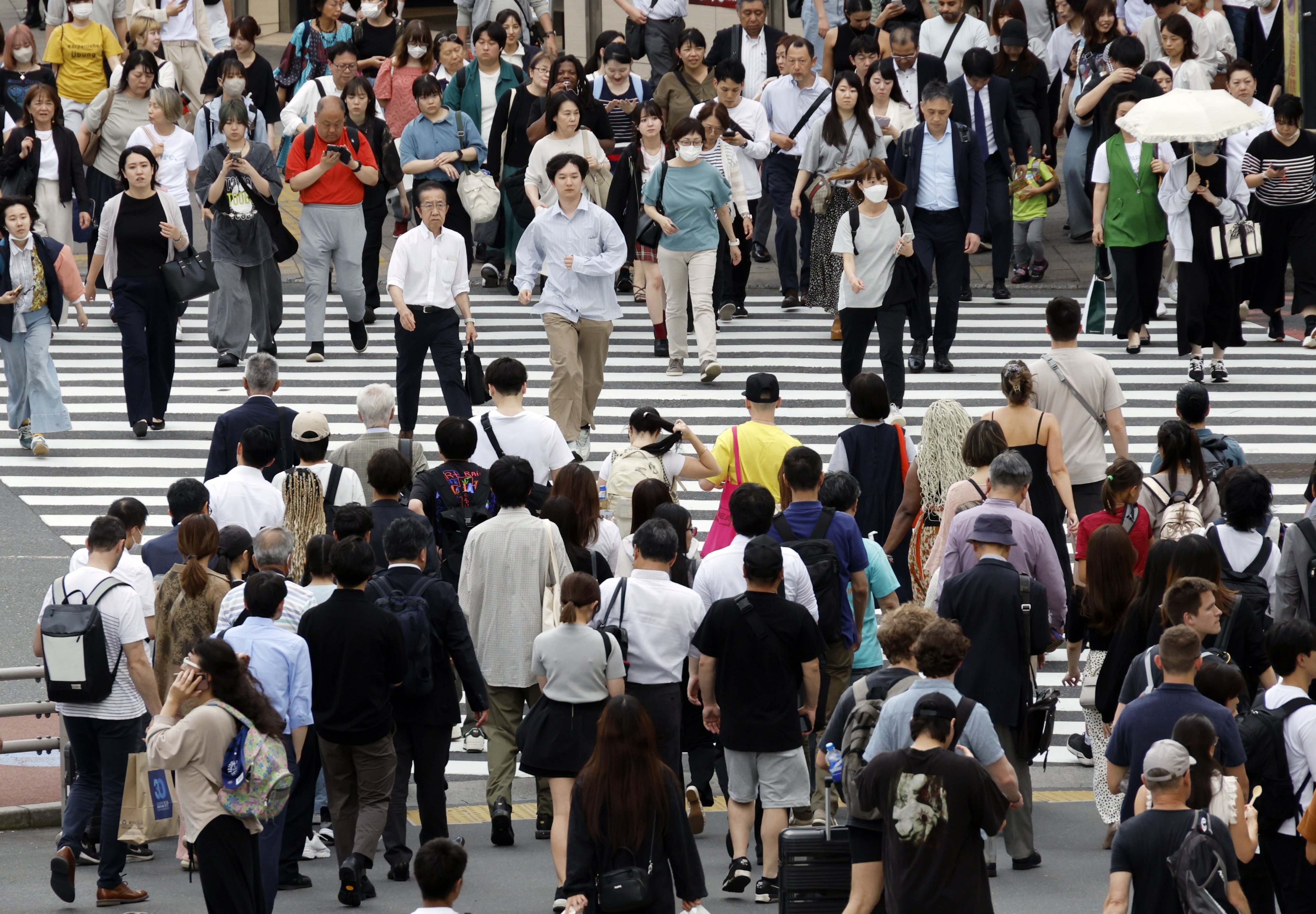 Pedestrians walk through a crossing in Tokyo. A lawmaker says Japan’s business manager visa has become an “easy route” to residency. Photo: EPA-EFE