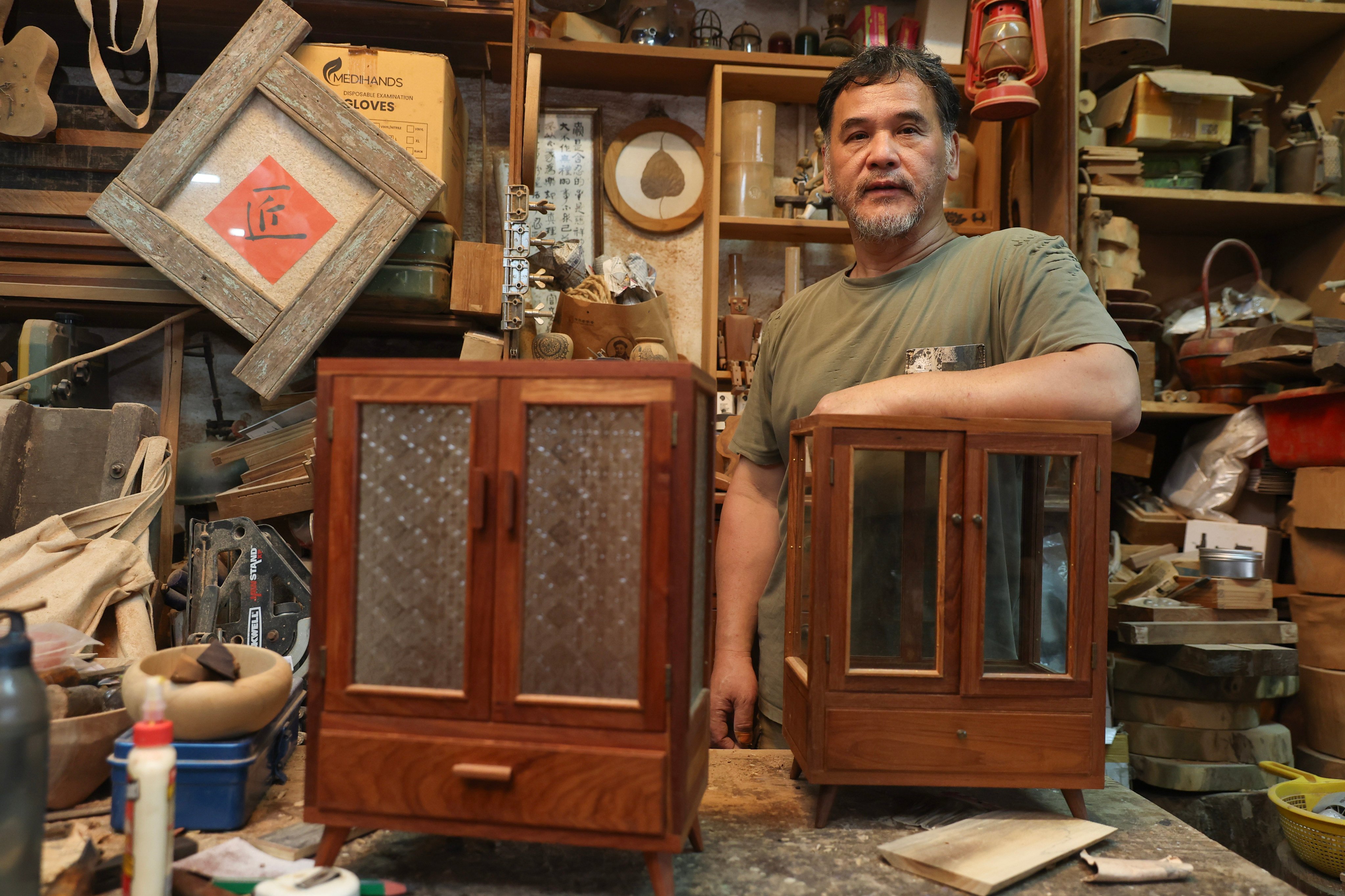 Timber artisan Lam Che stands with some of his furniture pieces at his workshop in Kwun Tong, Hong Kong, on June 4, 2025. Lam uses wood salvaged from fallen trees to make furniture including stools and tabletop accessories such as radio and jewellery cabinets. Photo: Edmond So