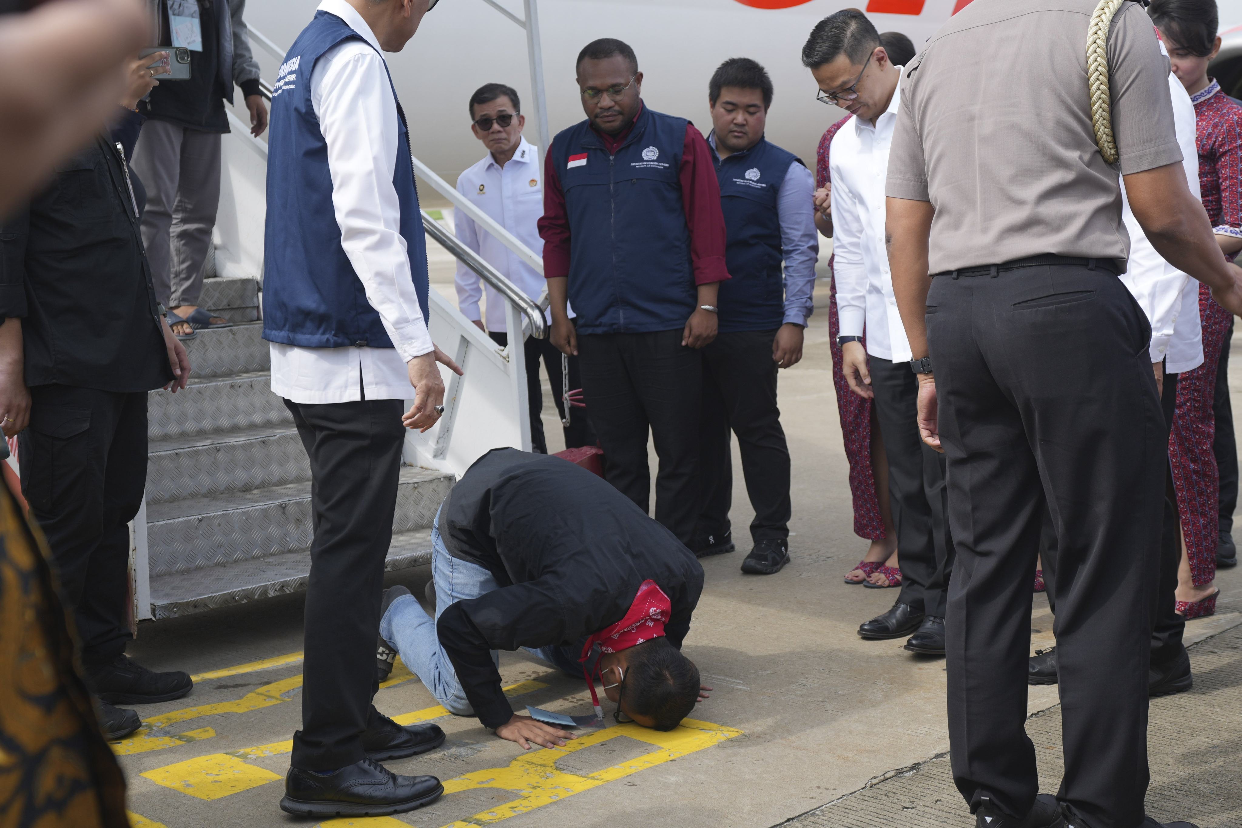 An Indonesian national rescued from Myanmar kisses the ground upon arrival at Soekarno-Hatta airport near Jakarta on March 18. Southeast Asian scam centres involve criminal gangs trafficking hundreds of thousands of people to help generate illicit revenues. Photo: AP