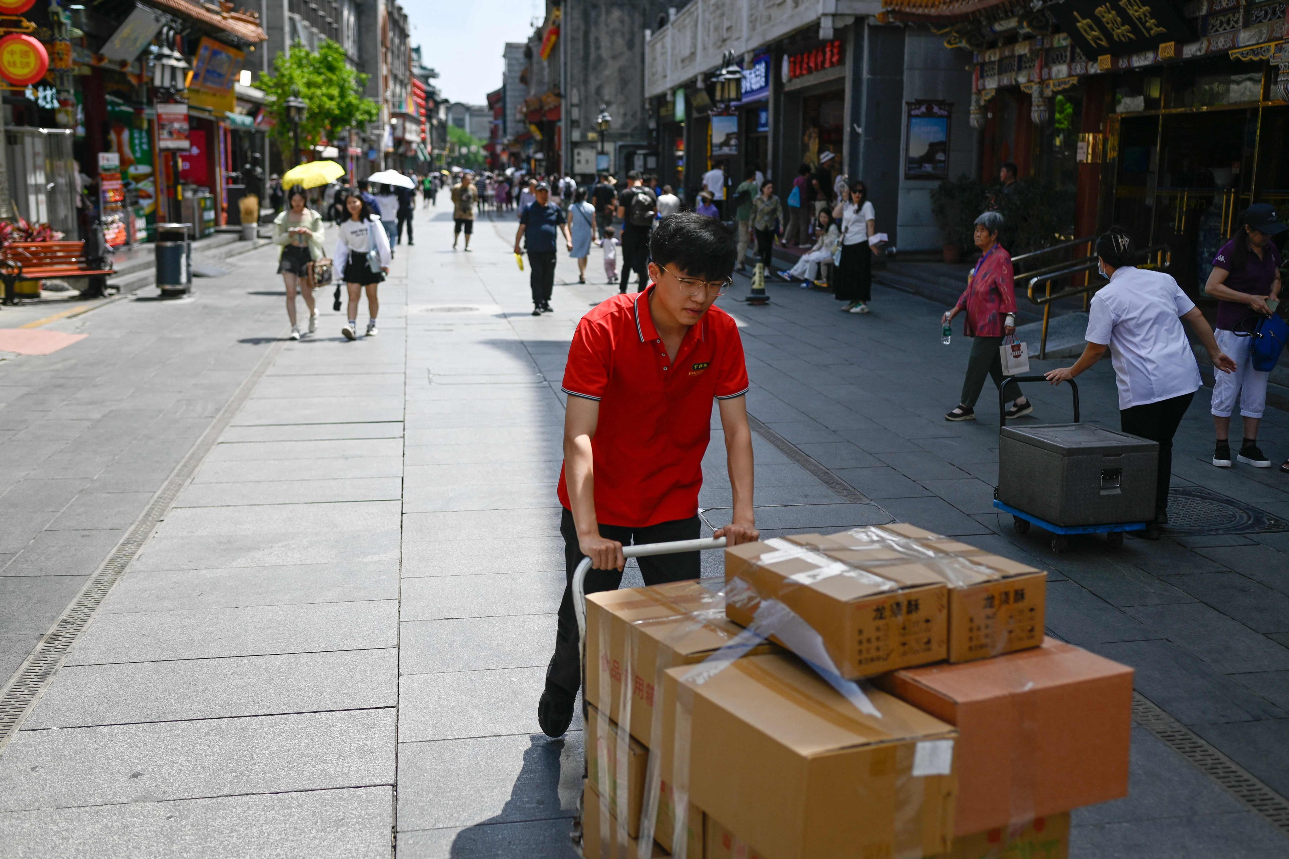 A man pushes a trolley loaded with boxes of food along a shopping street in Beijing on June 5. Photo: AFP