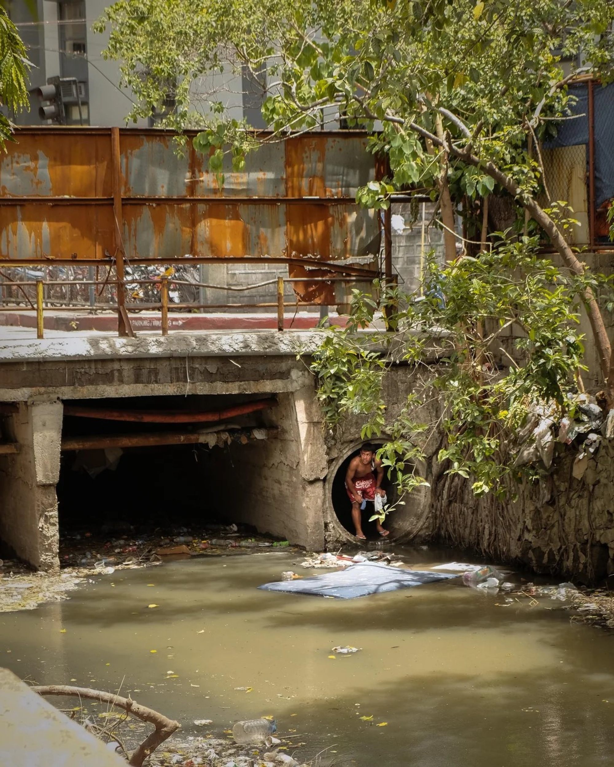 A man climbs out of a culvert in a creek in Makati City, apparently home to a small community of street dwellers in the Philippines. Photo: William Roberts