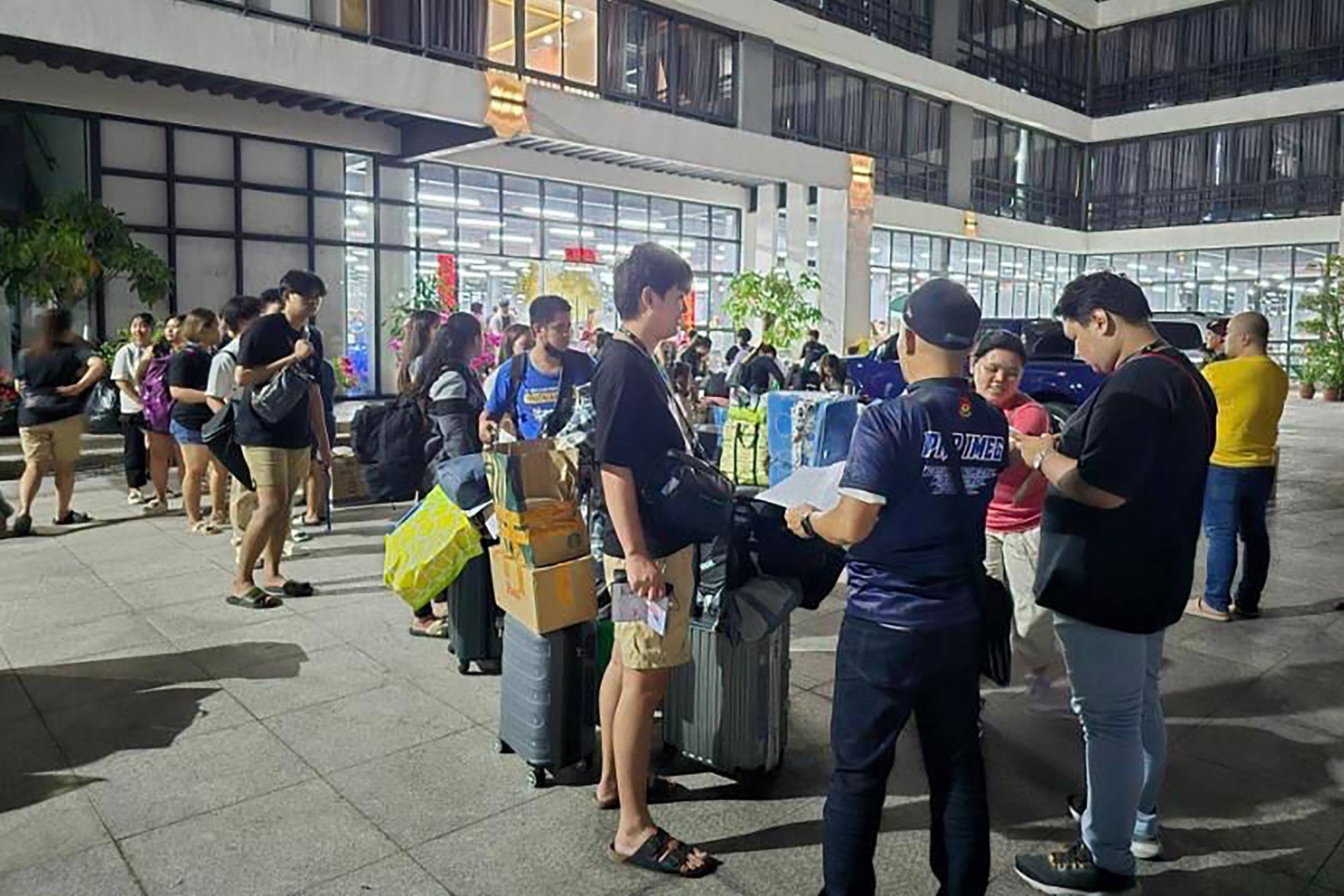 A police officer (front, centre) talks to foreign nationals after a raid in a complex of buildings in Bamban town of Tarlac province, north of Manila. Photo: Philippines’ Presidential Anti-Organised Crime Commission/AFP