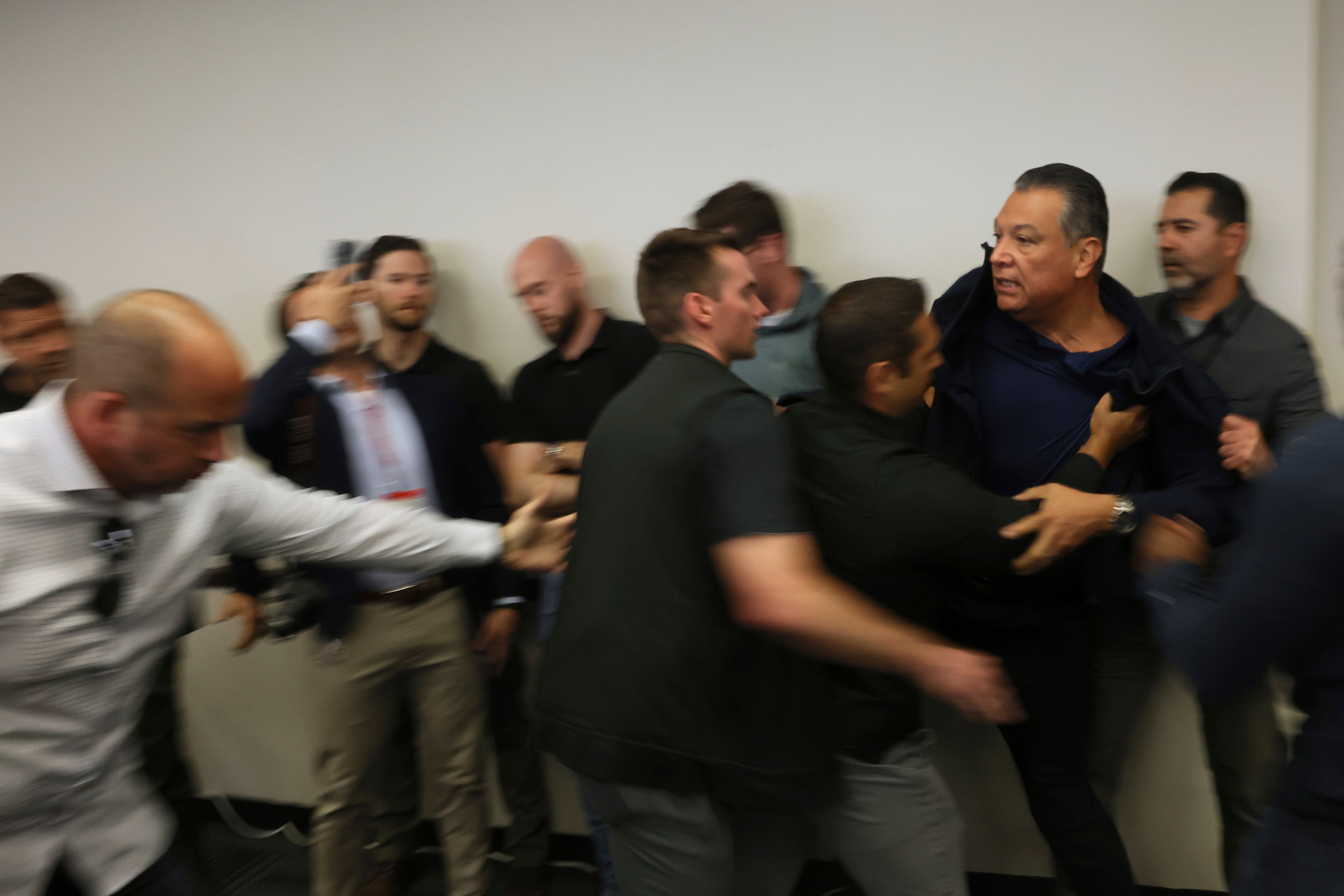 US Senator Alex Padilla being pushed out of the room as Homeland Security Secretary Kristi Noem holds a news conference. Photo: AP