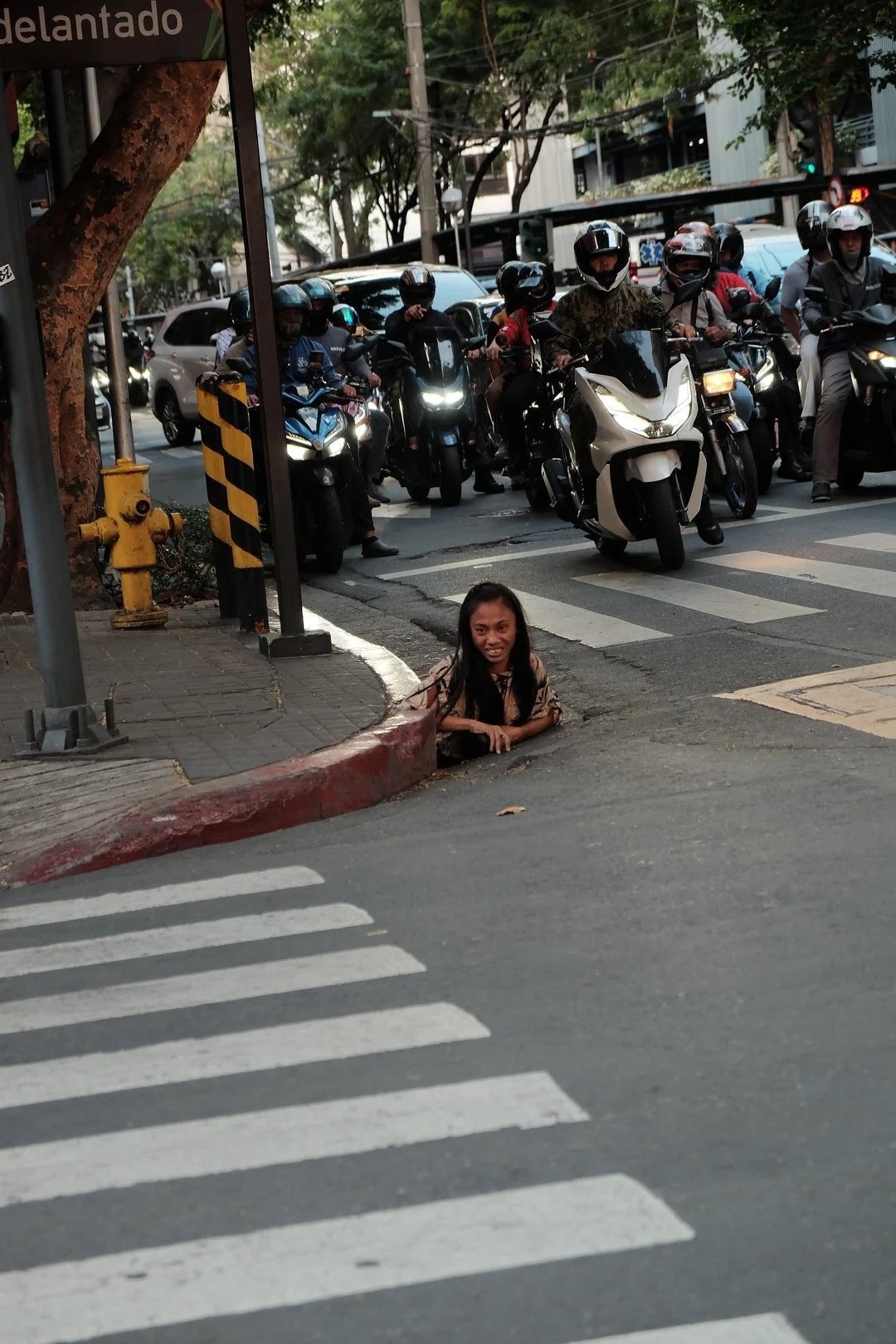 A woman is photographed emerging from a drainage hole along a street in Makati City in the Philippines. Photo: William Roberts