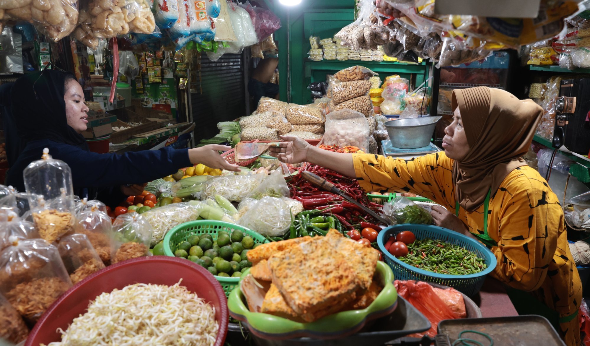 A produce seller serves a customer at a traditional market in Depok, Indonesia. The new stimulus includes rice and staple food aid for 18.3 million poor families. Photo: EPA-EFE