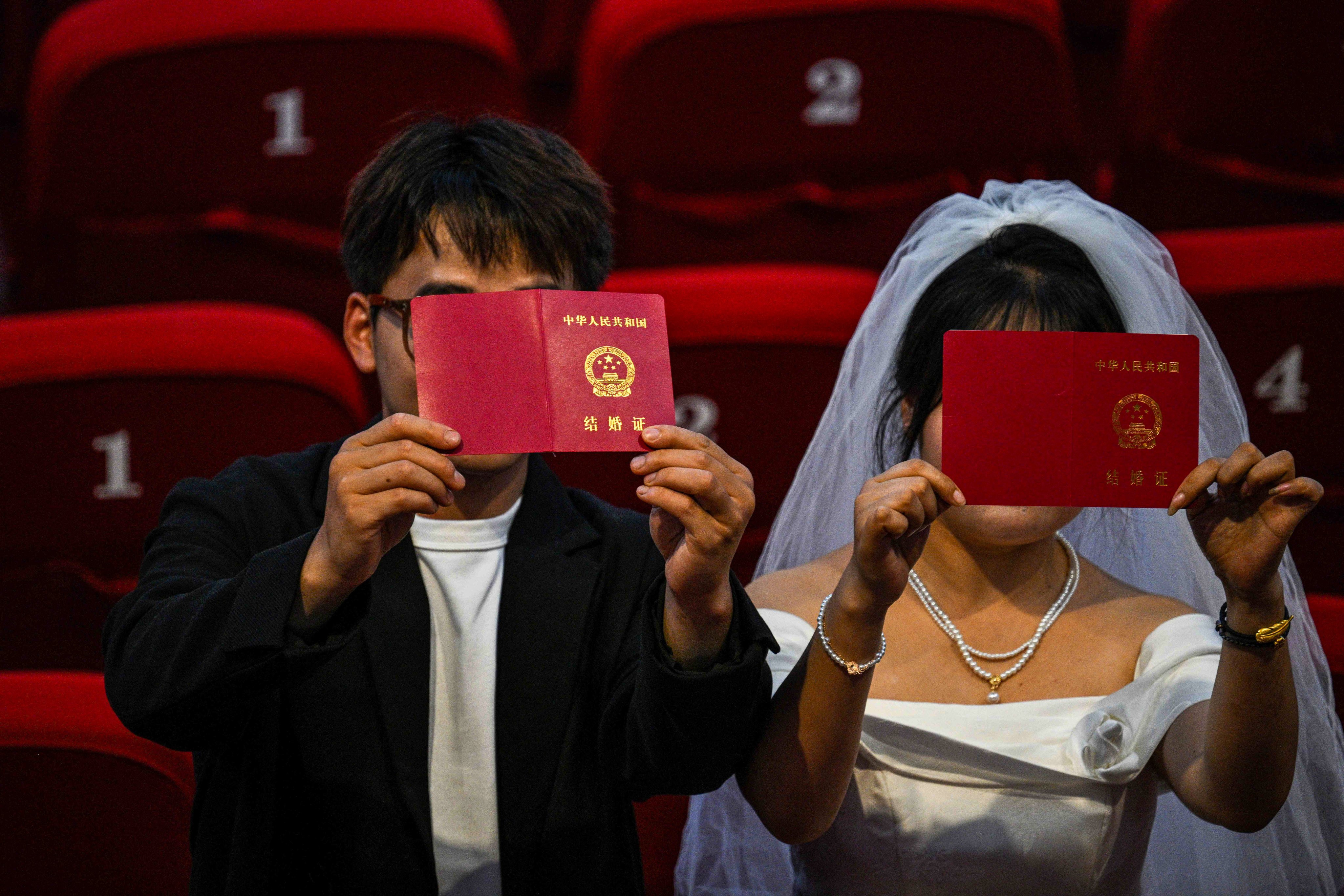 A Chinese couple holds up their marriage certificates. Rising separation rates in China have led to the emergence of divorce appointment booking agents taking advantage of an overwhelmed system. Photo: AFP