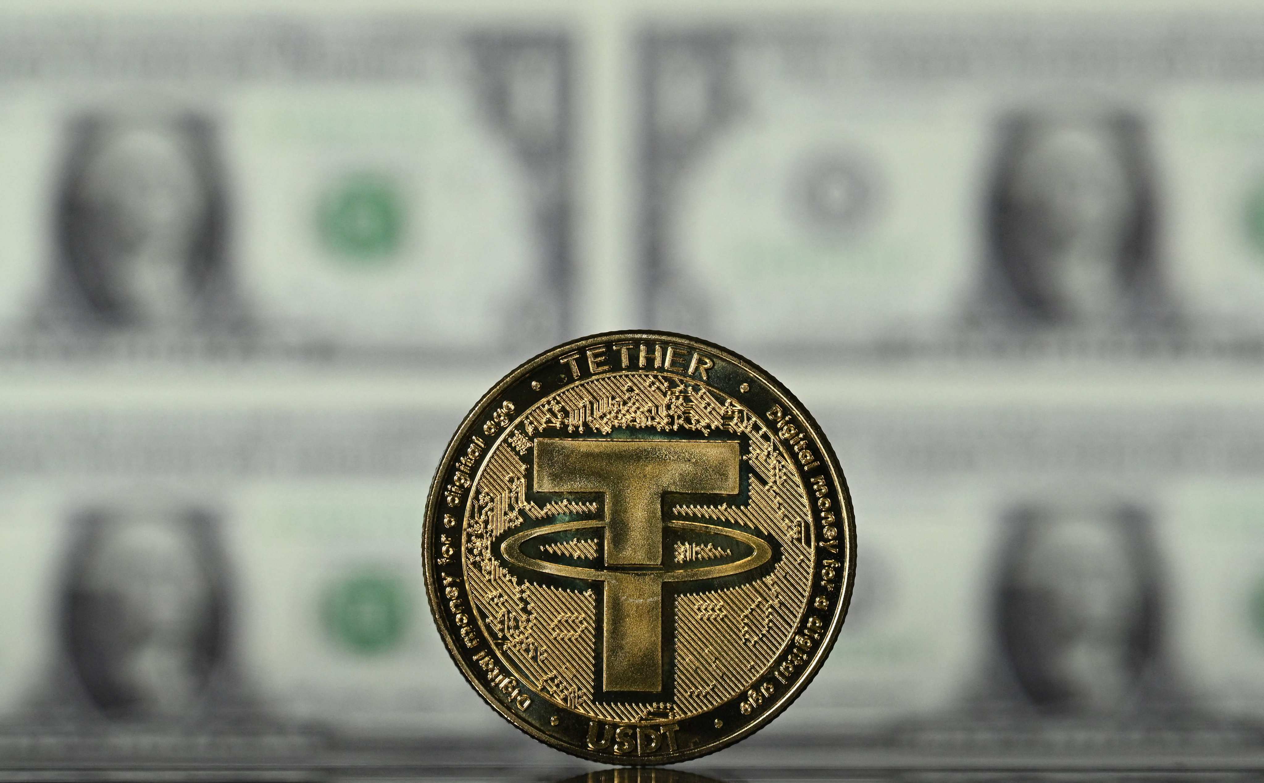 An illustration picture taken on May 8, 2022, shows a cryptocurrency Tether (USDT) coin arranged in front of a screen displaying US dollar notes. Photo: AFP