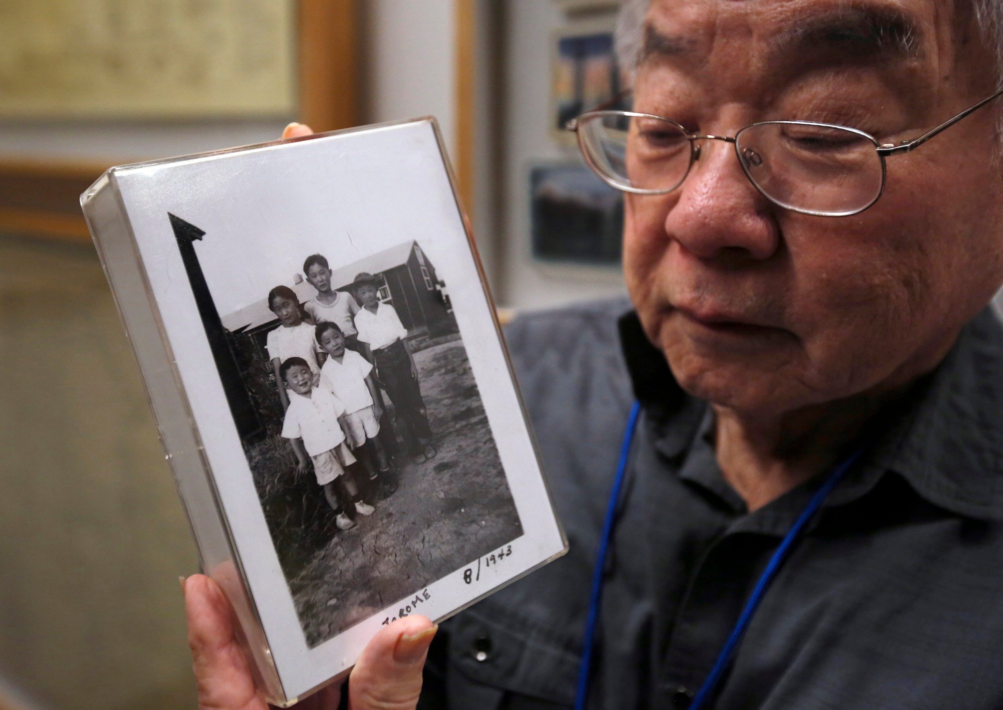 Les Ouchida holds a 1943 photo of himself and his siblings taken at a World War II internment camp, at an exhibit on Japanese American incarceration in Sacramento, California. Photo: AP