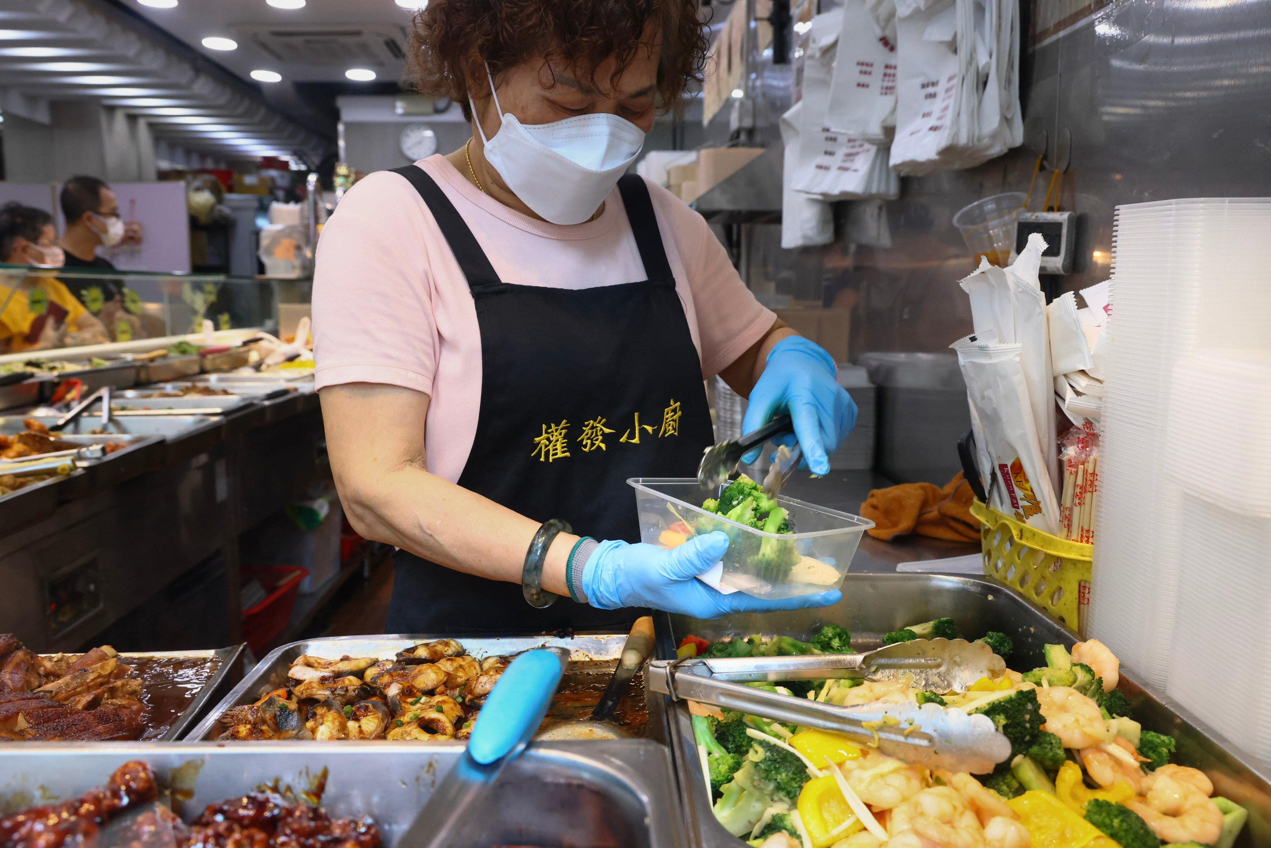 A worker puts food into a container for a customer to take away at a popular “two-dish rice” restaurant in Mong Kok, on May 24. Photo: Dickson Lee