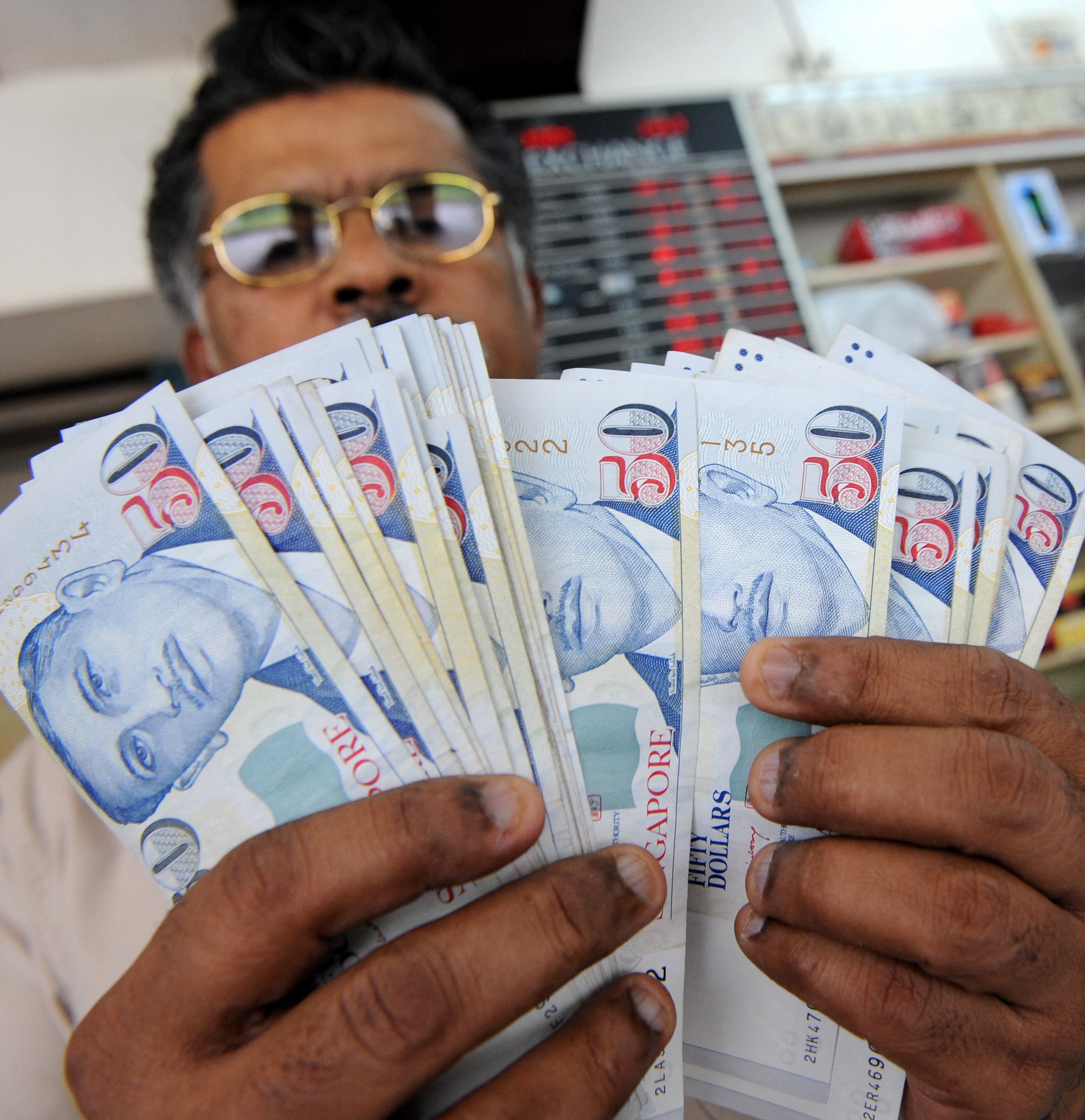 A dealer displays Singapore dollar notes at a money changer in Singapore. Photo: AFP