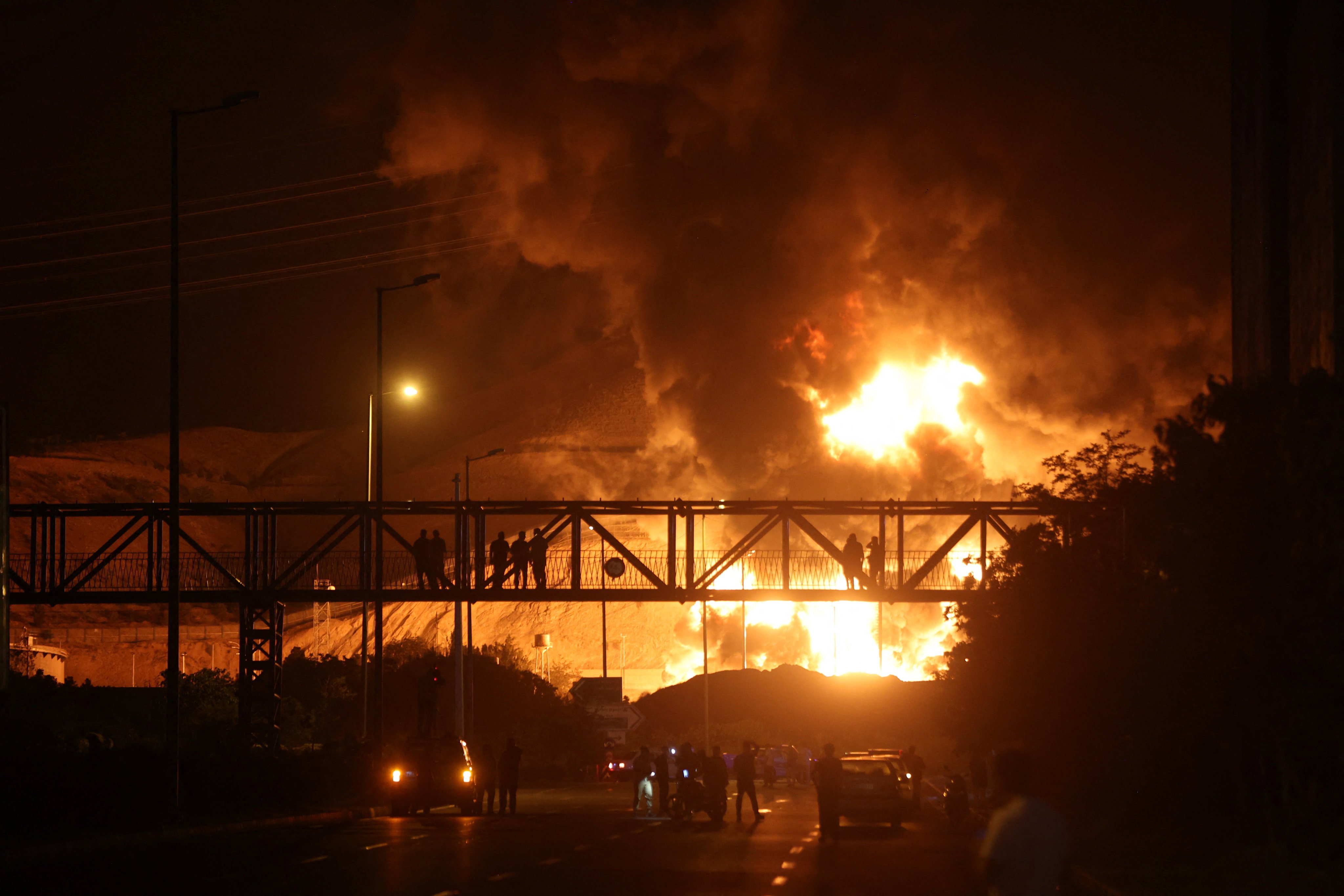 Pedestrians and drivers watch the Sharan Oil depot on fire following Israeli strikes, in Tehran, Iran, on Sunday. Photo: Reuters