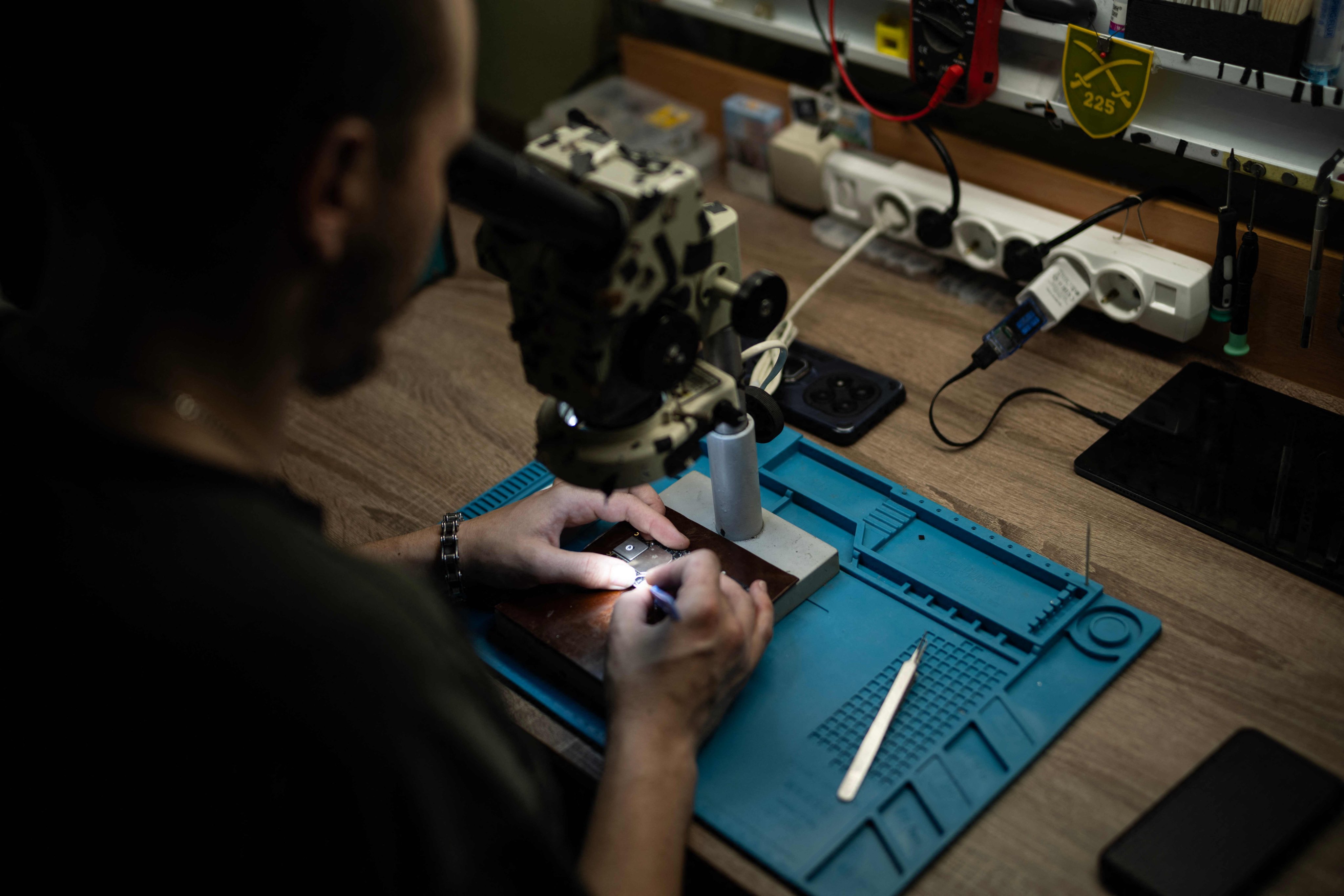 A soldier from the drone battalion of the 225th Ukrainian Separate Assault Regiment fighting near the Russian border in the Kursk region, looks through a microscope to solder a drone microprocessor in a drone workshop in an undisclosed location on June 12. Photo: AFP