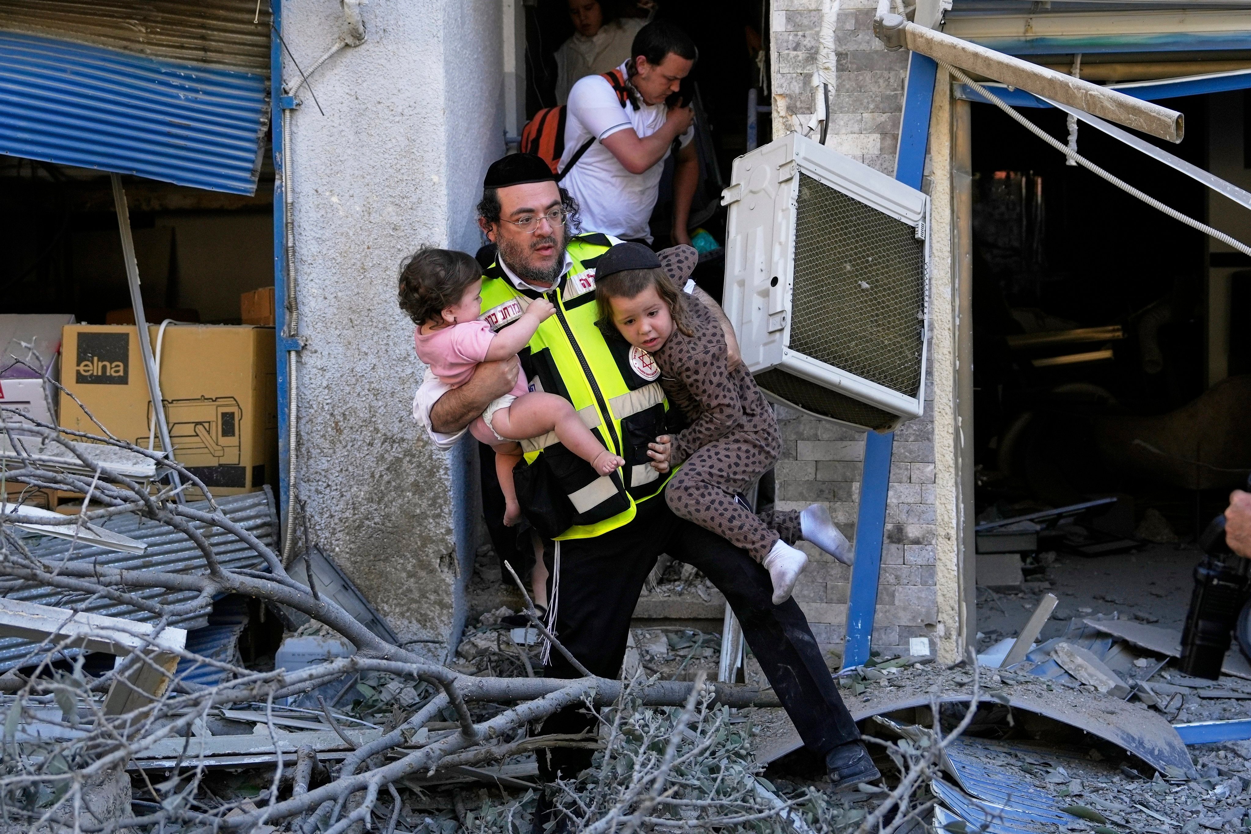 A rescuer evacuates two children from the site where a missile launched from Iran struck in Haifa, Israel, on Sunday. Photo: AP