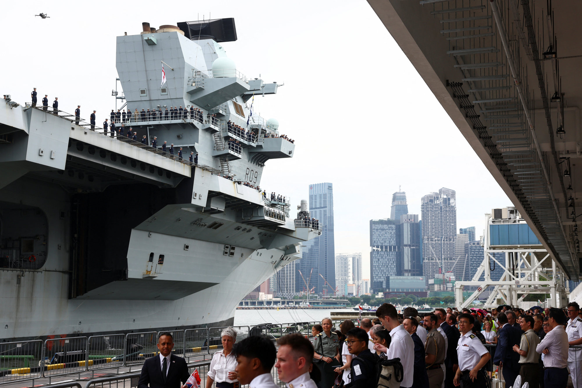 People watch as the HMS Prince of Wales aircraft carrier arrives at Marina Bay Cruise Centre in Singapore on Monday. Photo: Reuters People watch as the HMS Prince of Wales aircraft carrier arrives at Marina Bay Cruise Centre in Singapore on Monday. Photo: Reuters