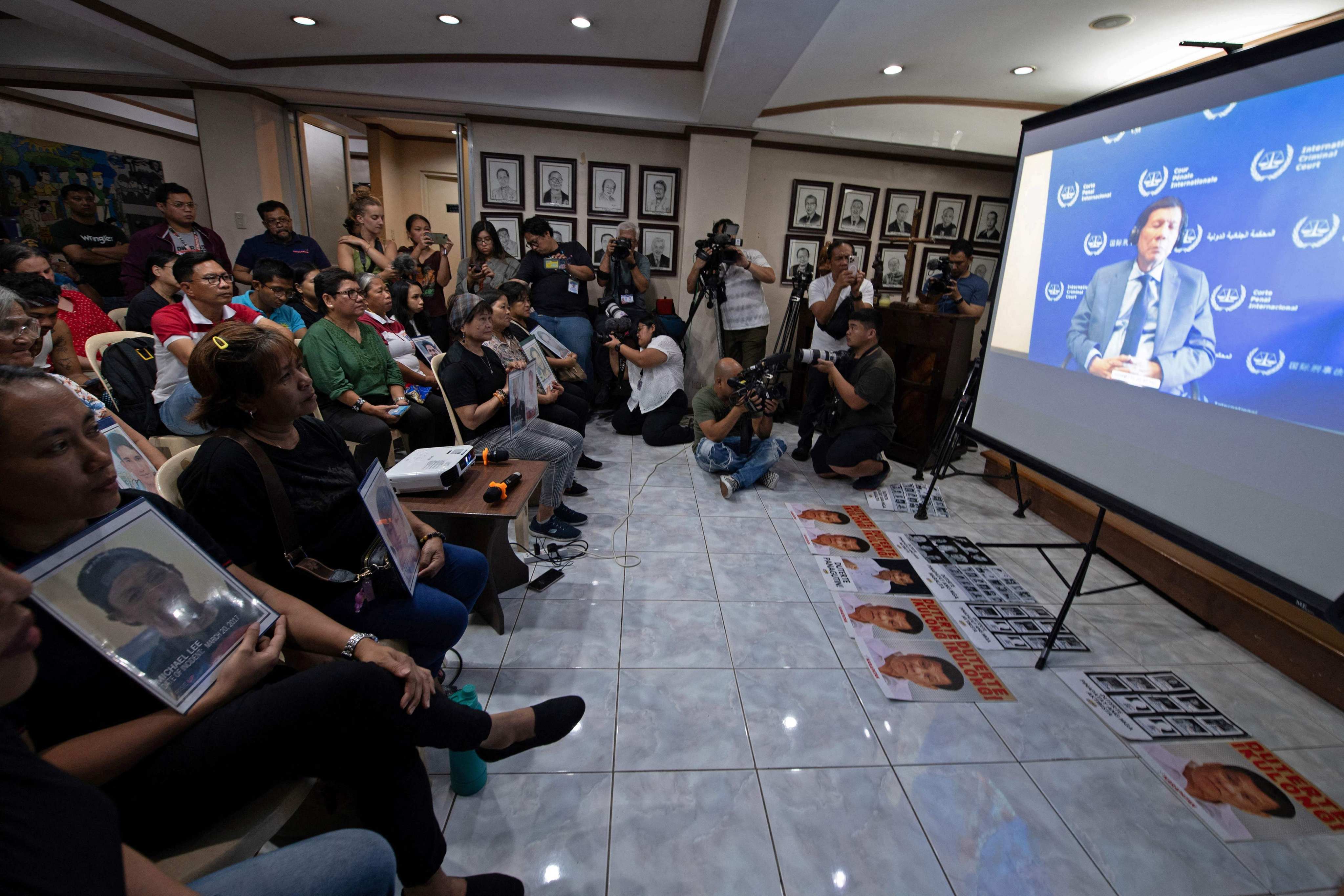 Families holding portraits of victims of former Philippines president Rodrigo Duterte’s drug war watch a live stream of Duterte’s first appearance at the International Criminal Court on March 14. Photo: AFP