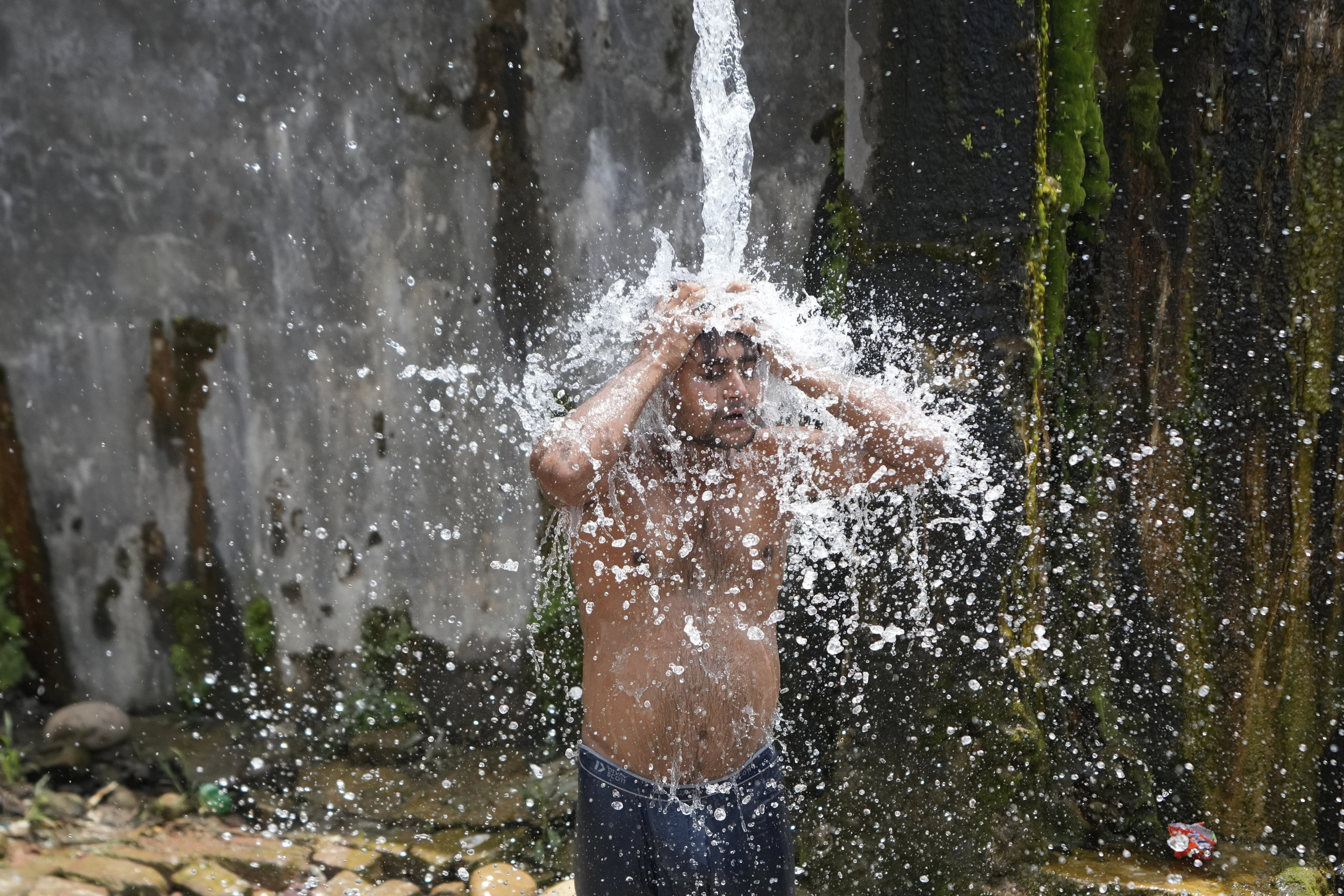 A man in Jammu, India, bathes from a roadside water tap on June 15 to cool himself off on a hot summer day. Photo: AP