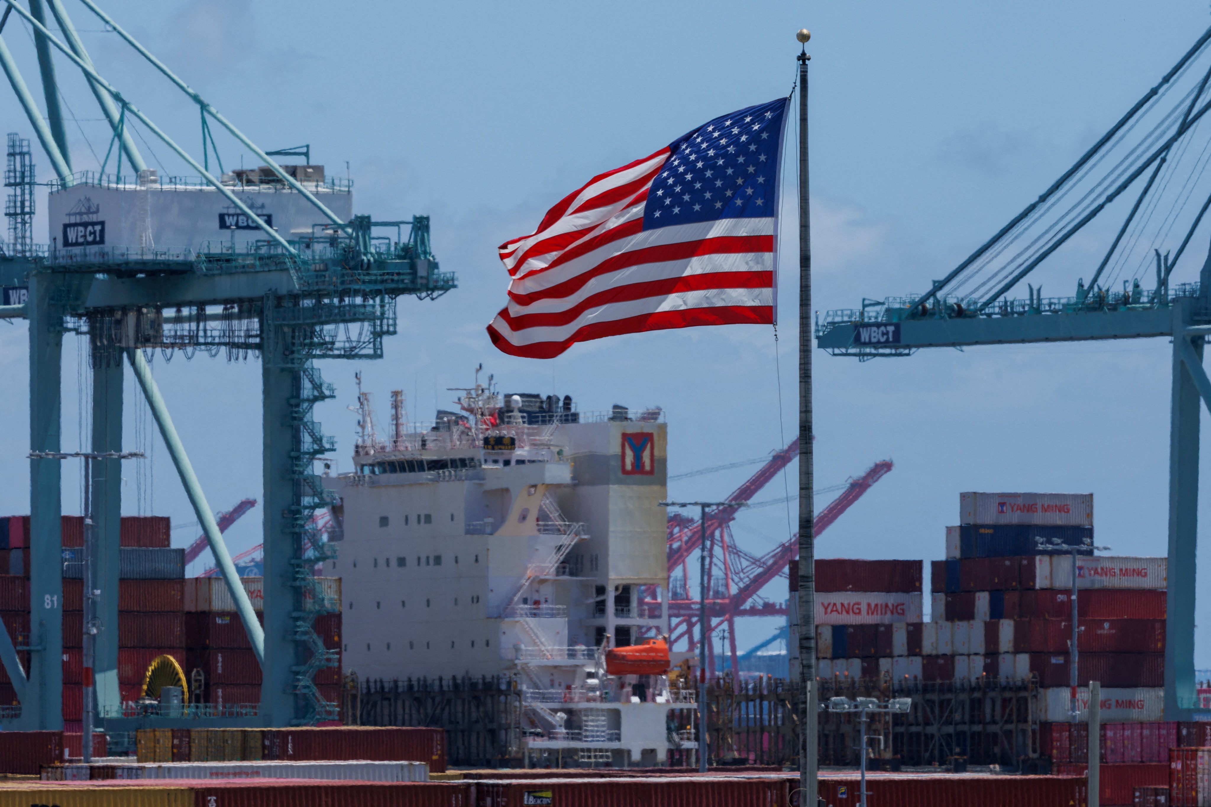 An American flag flutters over a ship and shipping containers at the Port of Los Angeles, in California. The threat of new US tariffs starting in early July is forcing companies to get goods onto vessels and to the US as quickly as possible. Photo: Reuters