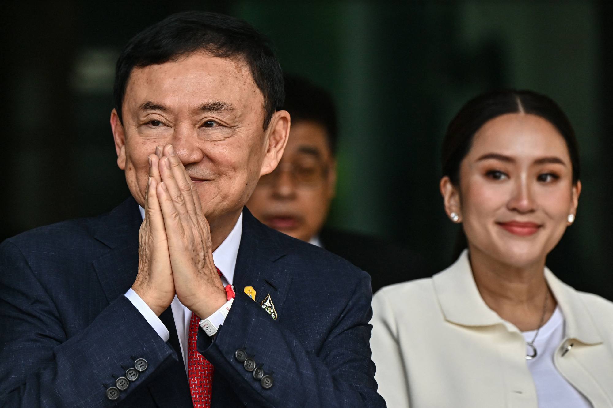 Former Thai prime minister Thaksin Shinawatra greets supporters alongside his daughter Paetongtarn Shinawatra at Don Mueang airport in Bangkok in 2023. Thaksin is due to stand trial for royal defamation, while Paetongtarn faces growing pressure as prime minister amid a deepening political crisis. Photo: AFP Former Thai prime minister Thaksin Shinawatra greets supporters alongside his daughter Paetongtarn Shinawatra at Don Mueang airport in Bangkok in 2023. Thaksin is due to stand trial for royal defamation, while Paetongtarn faces growing pressure as prime minister amid a deepening political crisis. Photo: AFP