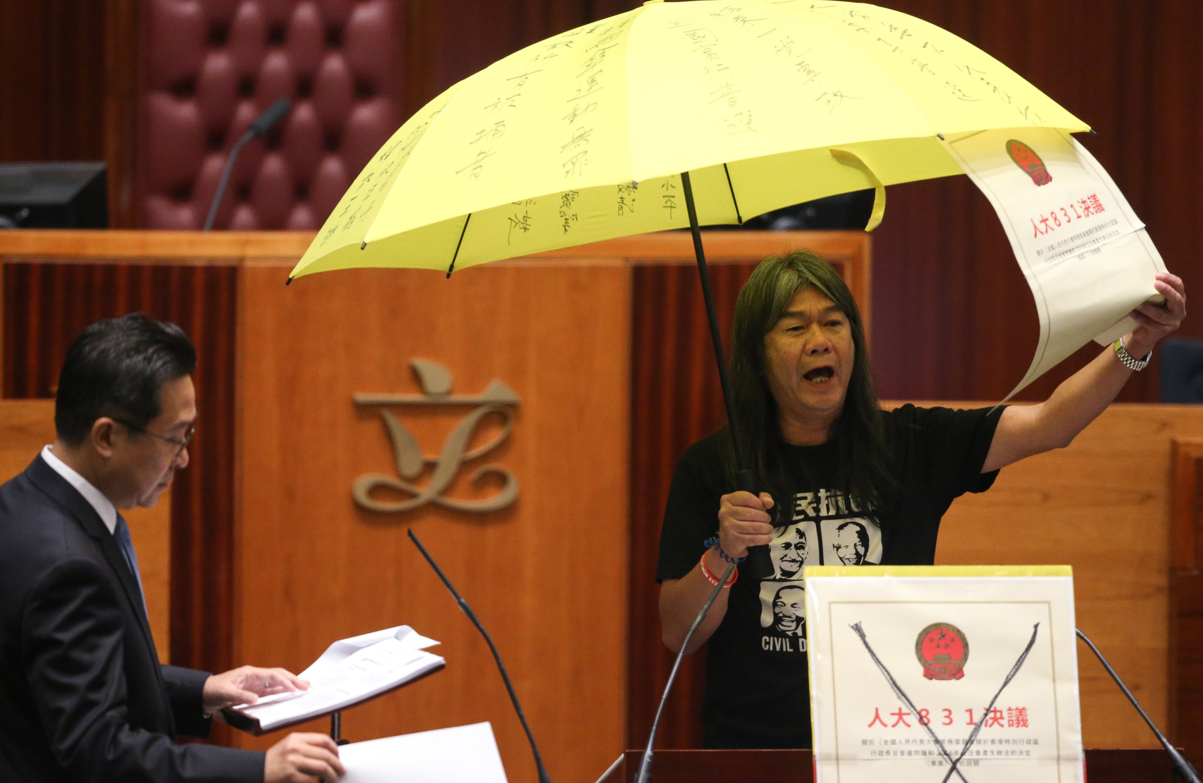Leung Kwok-hung protests during the oath-taking session while Legco Secretary General Kenneth Chan Wei-on looks on in October . 2016. Photo: Sam Tsang