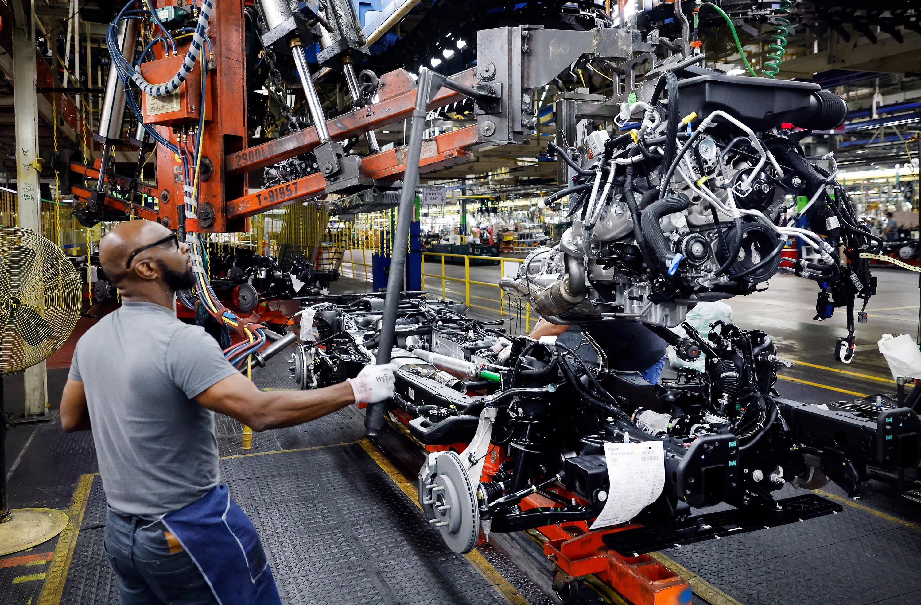 Assembly team worker Kevin Garner lowers the engine assembly onto the frame of a large SUV at a General Motors assembly plant in Arlington, Texas. Photo: The Dallas Morning News/TNS