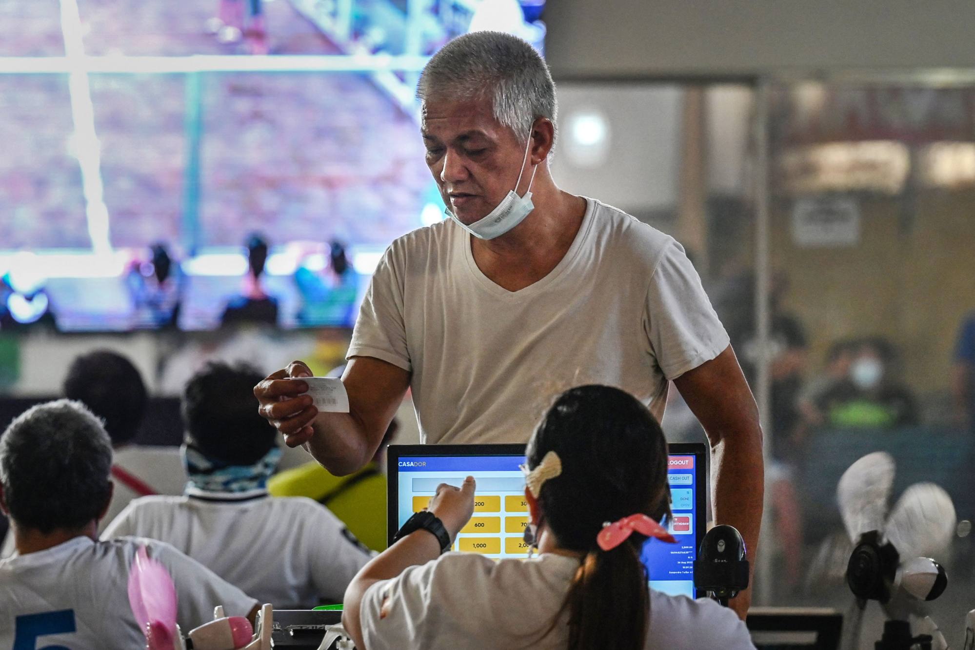 A man places his bet on a cockfighting match being displayed on a big screen at the San Pedro Coliseum in Laguna province in the Philippines. Online cockfighting raked in US$124 million in 2021 alone. Photo: AFP