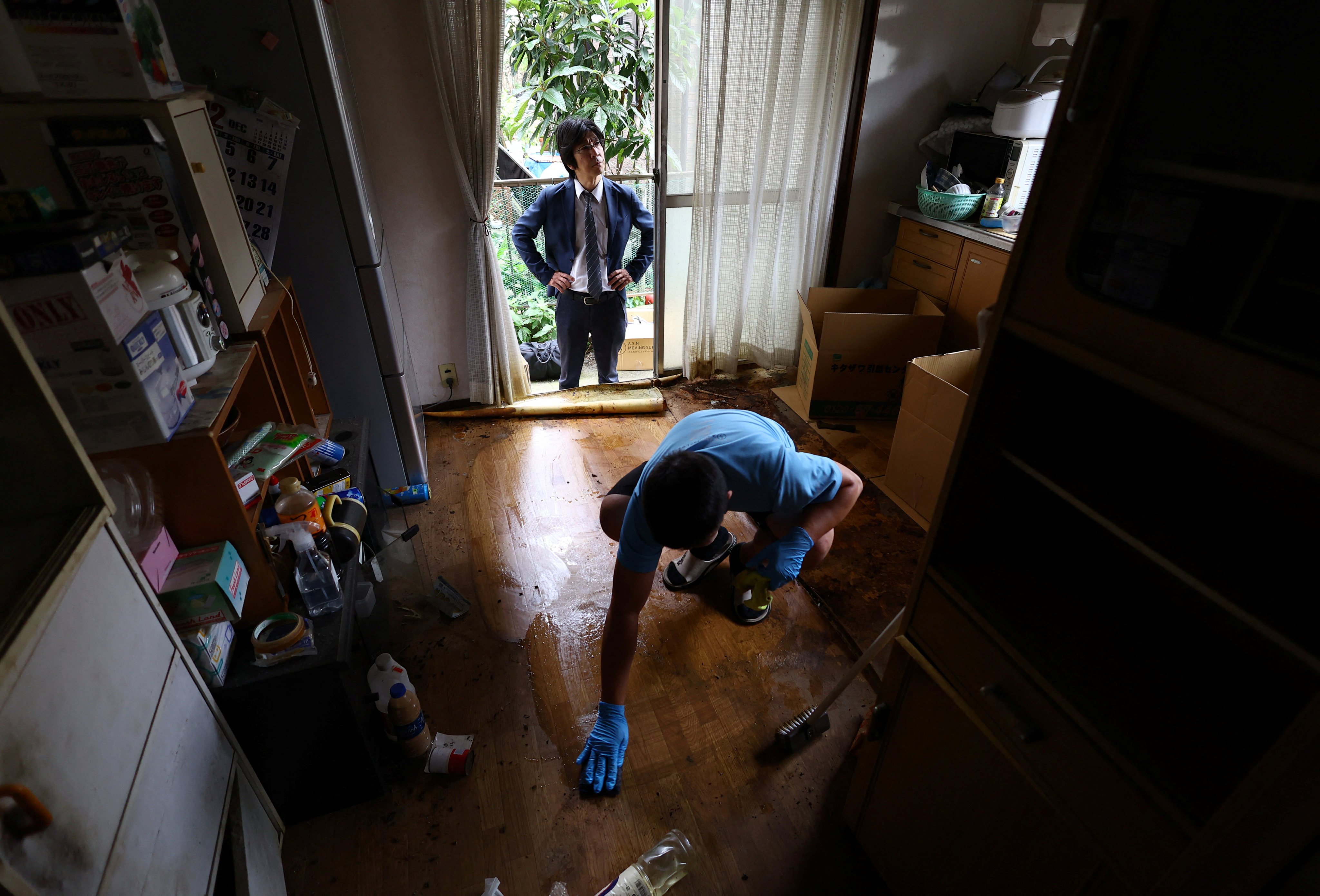 A property broker looks on while a worker cleans the floor in a house in Japan classified as a “jiko bukken”. Photo: Reuters
