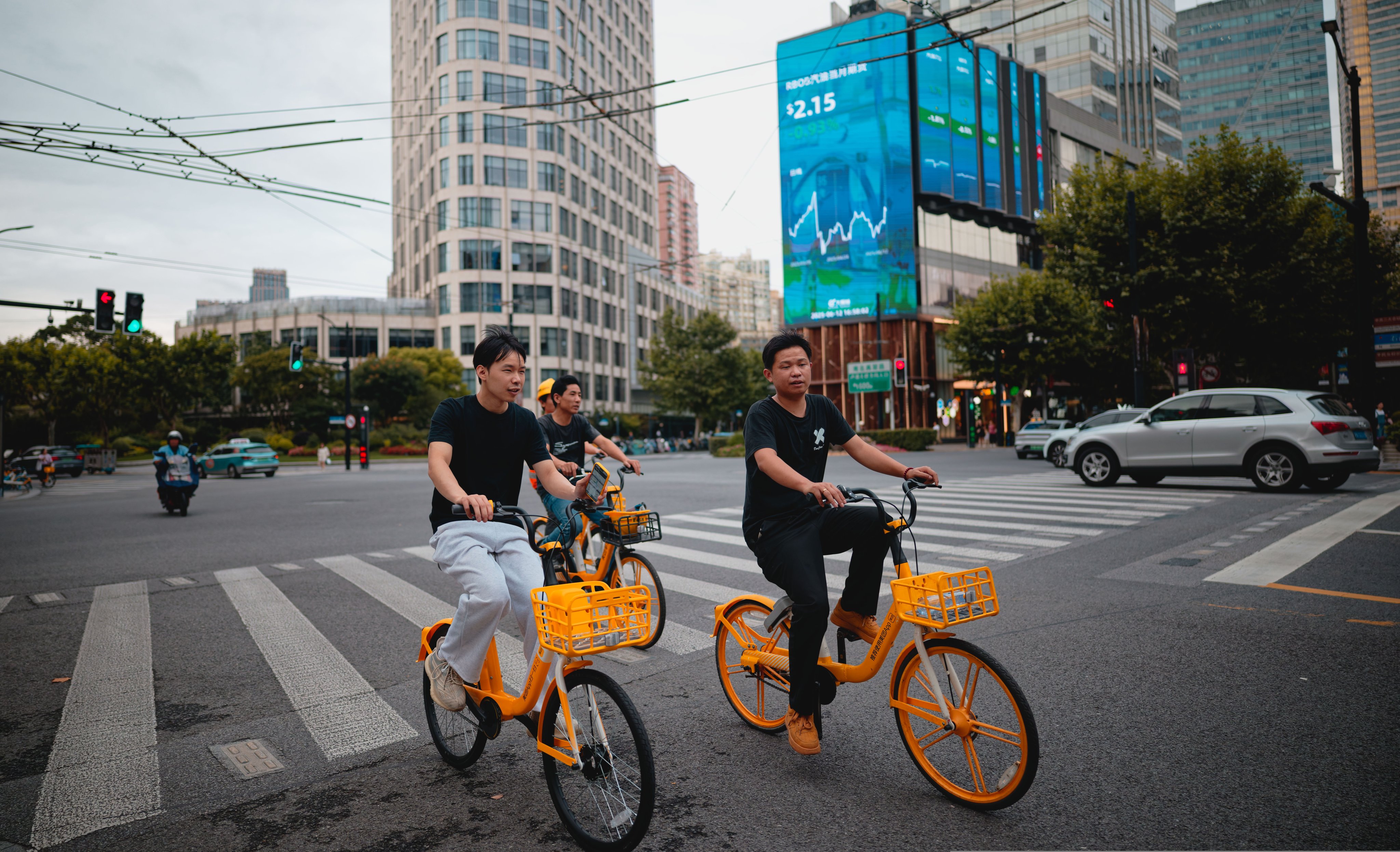 People cycling near a building showing the latest stock data in Shanghai on June 12, 2025. Photo: EPA-EFE