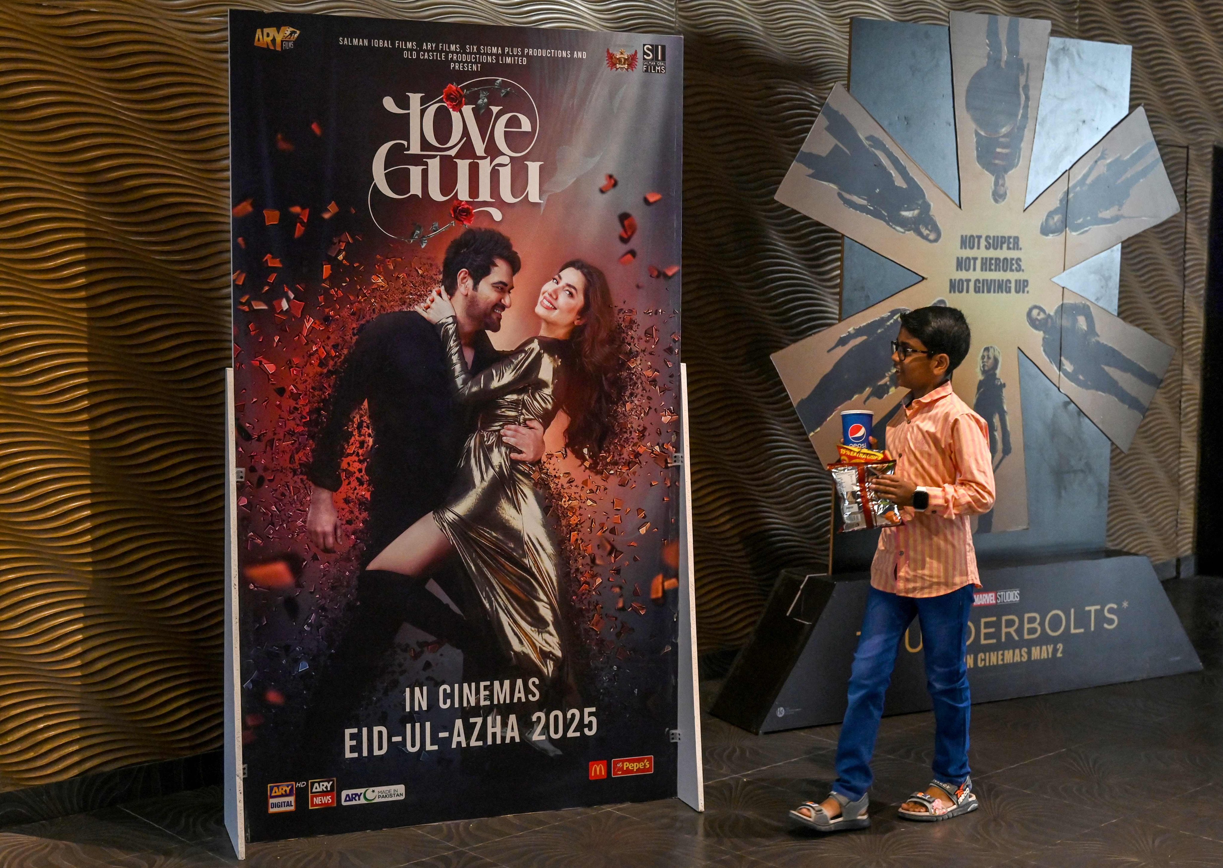 A young boy walks past a poster advertising the film “Love Guru”, featuring Pakistani actress Mahira Khan, in Lahore earlier this month. Photo: AFP