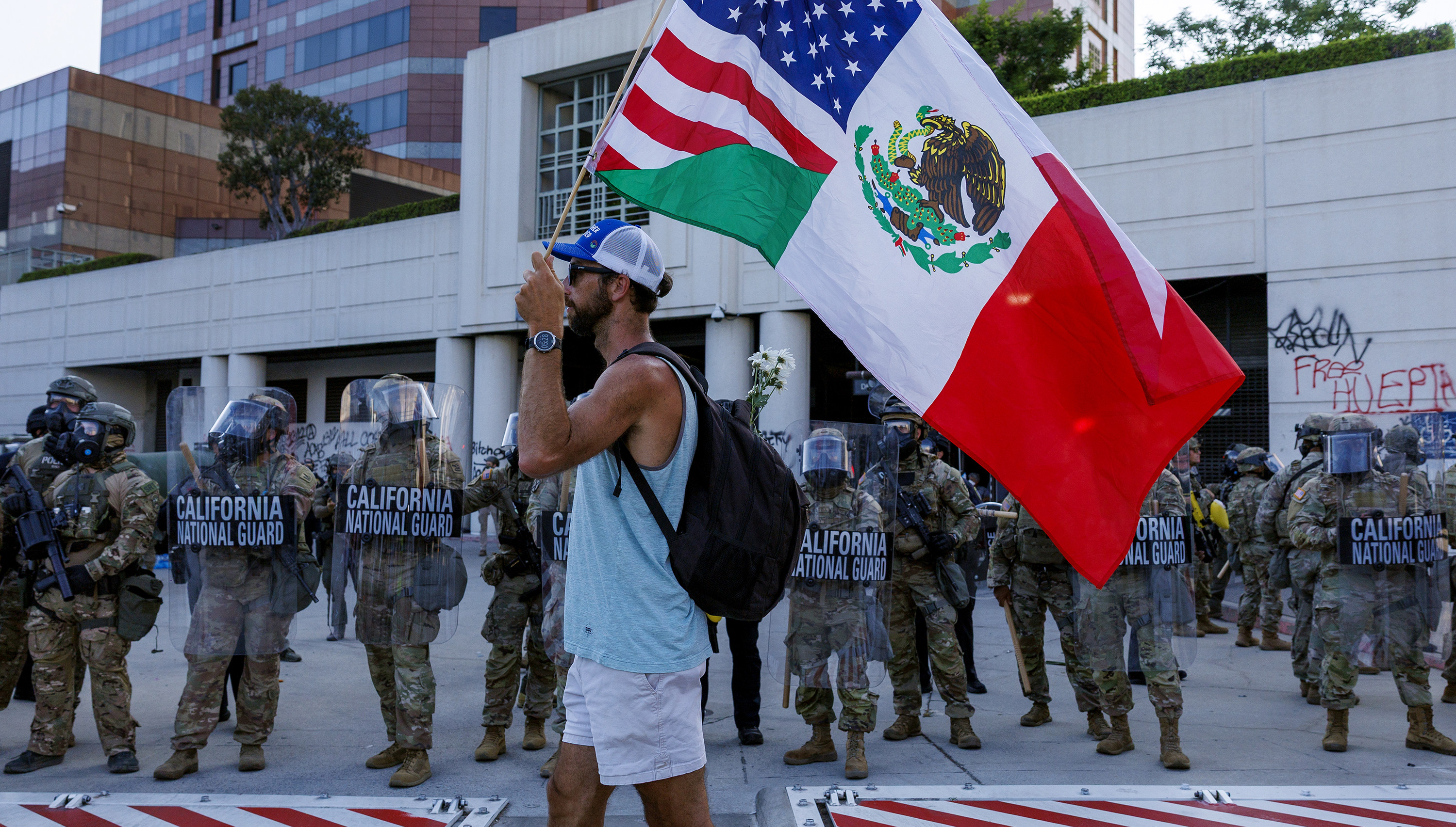 A protester carries US and Mexican flags while demonstrating in front of the California National Guard outside the Federal Building in Los Angeles on June 12. Photo: TNS