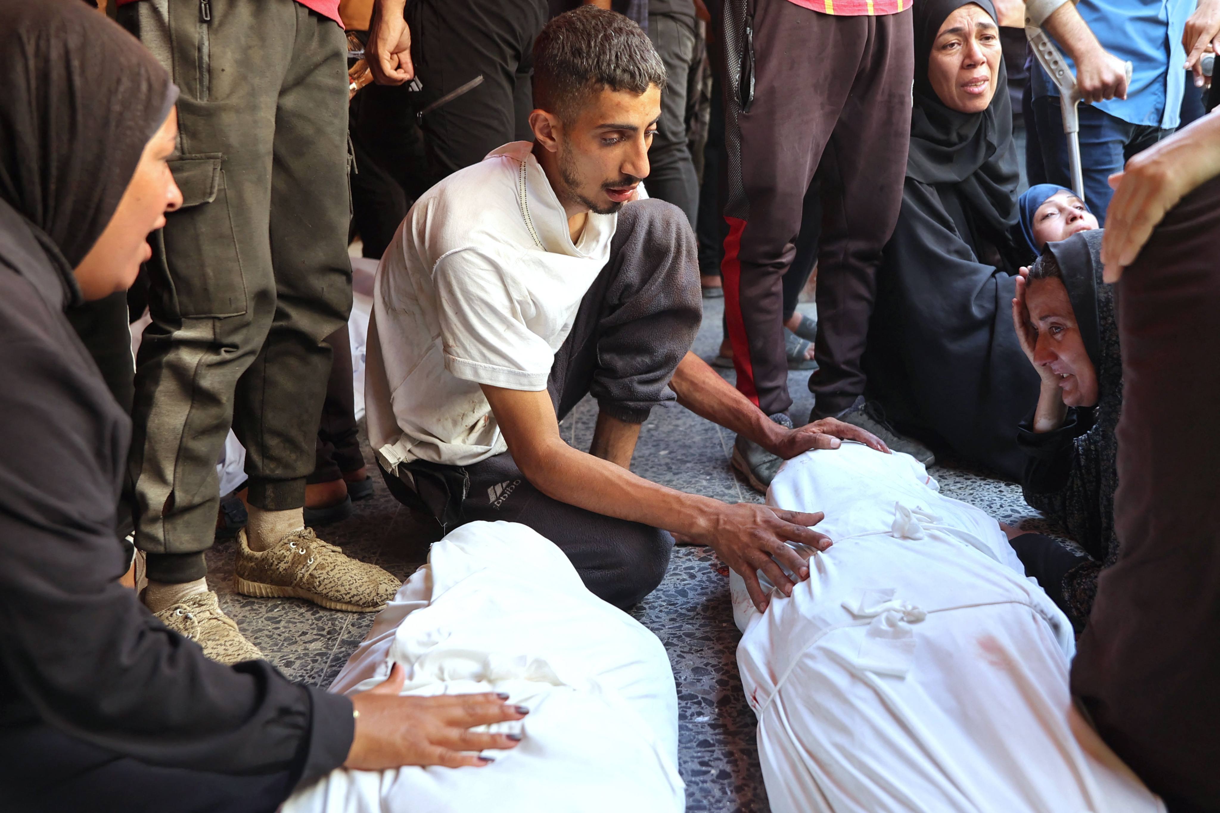 Palestinians mourn over the shrouded bodies of people killed during a reported Israeli strike on a humanitarian aid distribution warehouse. Photo: AFP