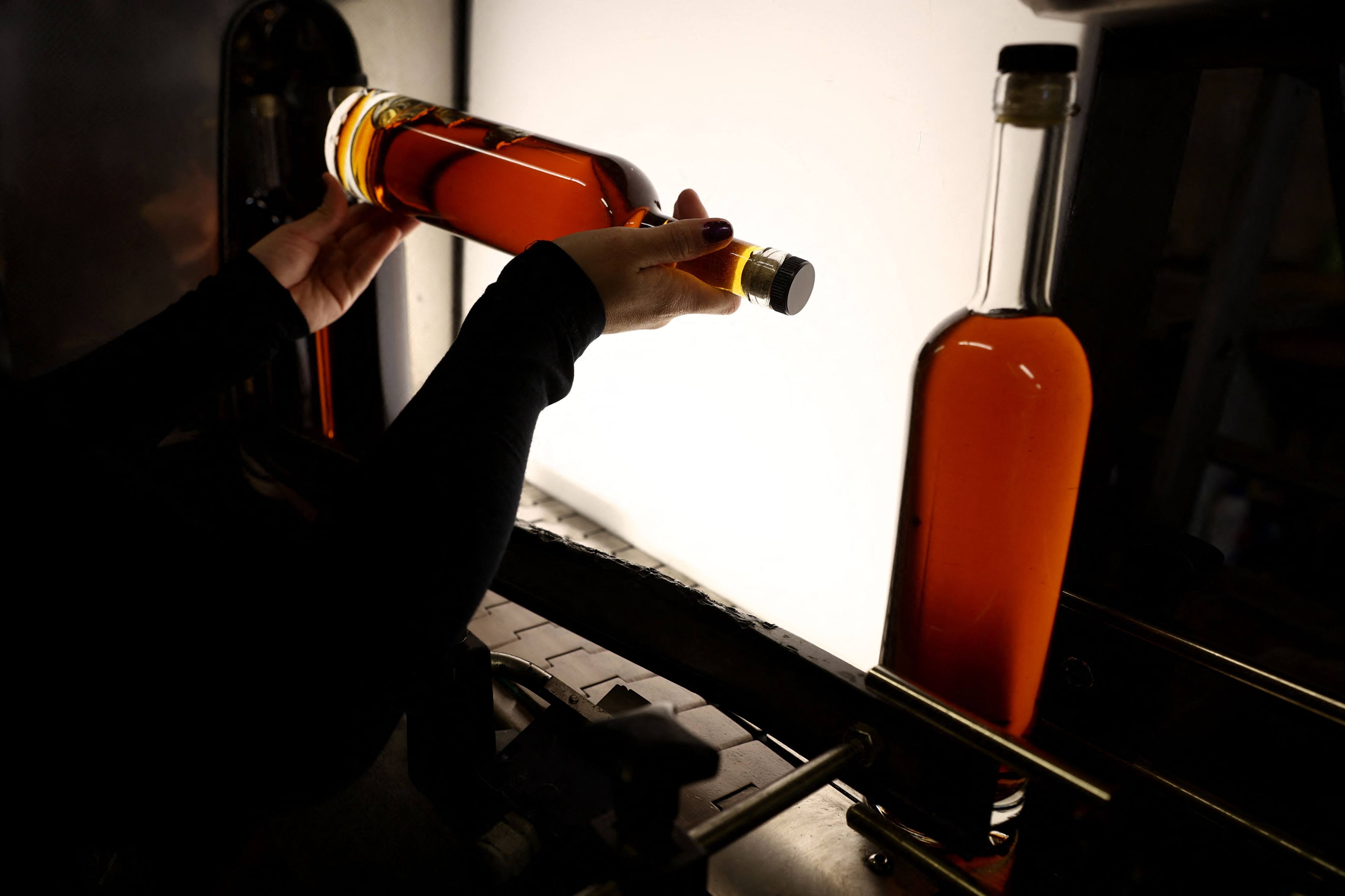 An employee checks cognac bottles on the bottling line of Chateau de Montifaud cognac producer in Jarnac-Champagne, south-western France, on March 20, 2025. Photo: AFP/Romain Perrocheau
