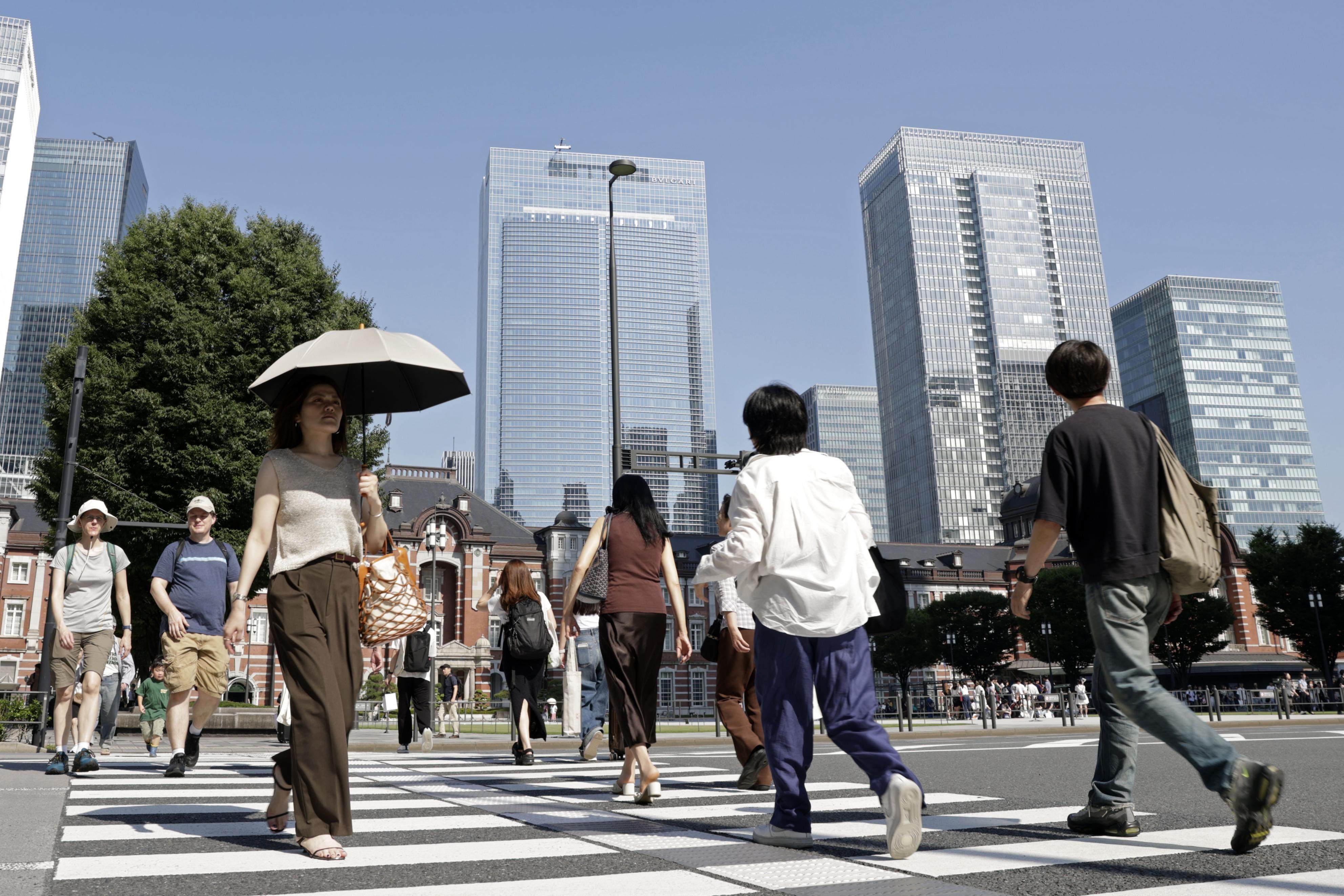 People walk under the scorching sun in front of JR Tokyo Station on June 17 as the temperature reaches 34.8 degrees Celsius. Photo: Kyodo