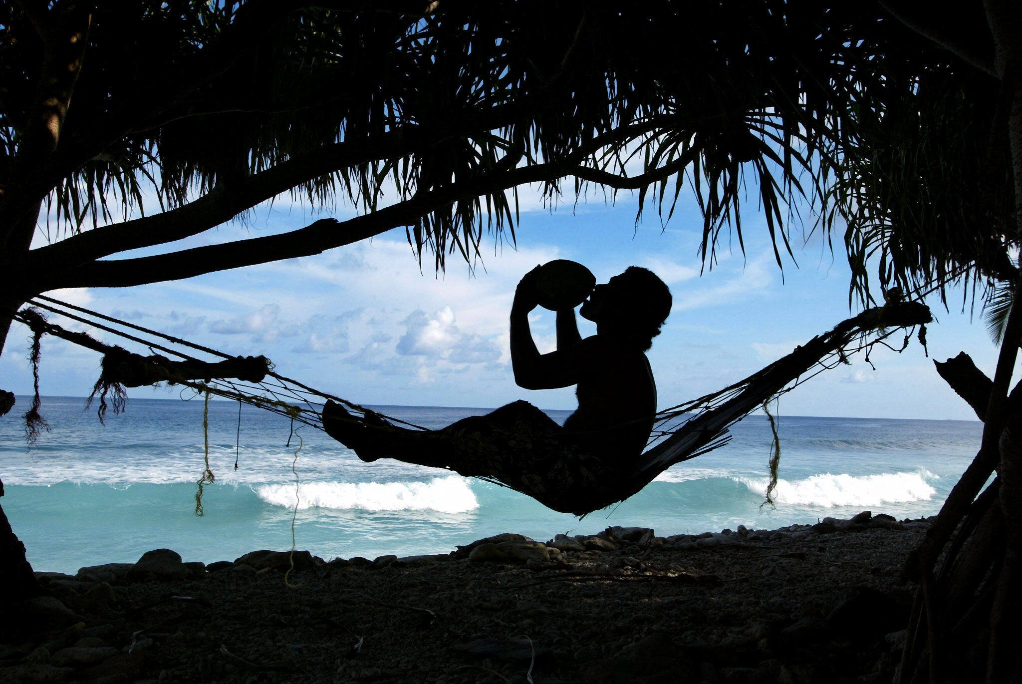 A man sat in a hammock drinks coconut milk on Funafuti Atoll, Tuvalu. Photo: AFP