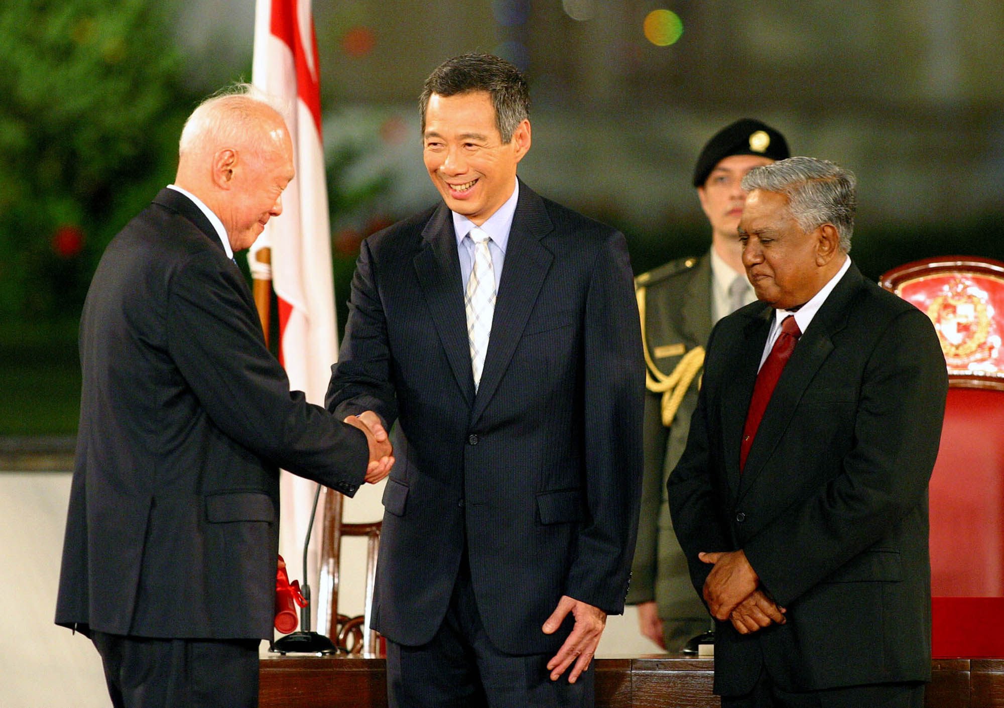 Newly appointed Singaporean Prime Minister Lee Hsien Loong (centre) shakes hands with his father, Minister Mentor Lee Kuan Yew, as President S.R. Nathan (right) looks on in 2004. Photo: AP