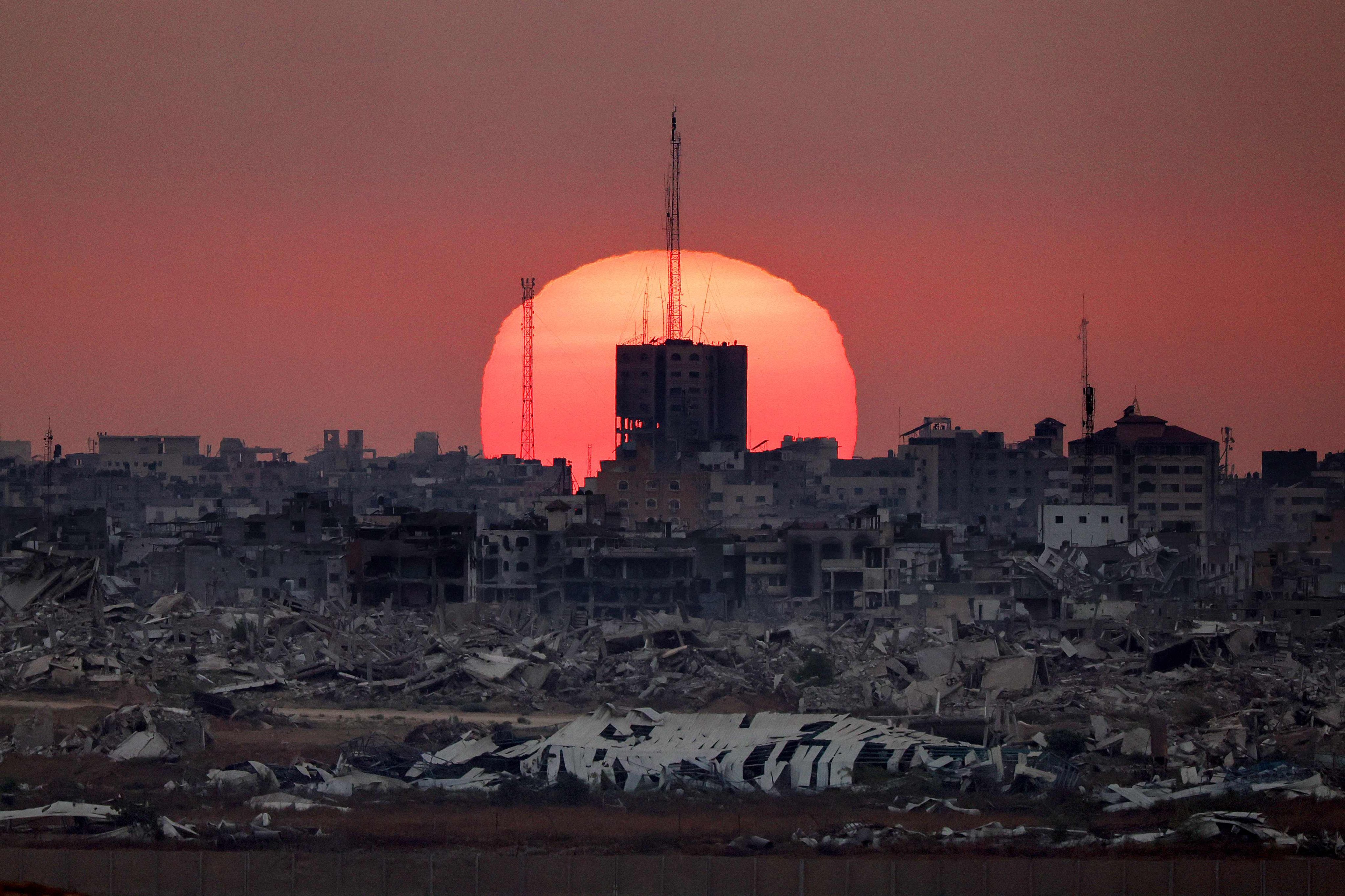 The sun setting behind destroyed buildings in the Gaza Strip on Tuesday. Photo: AFP