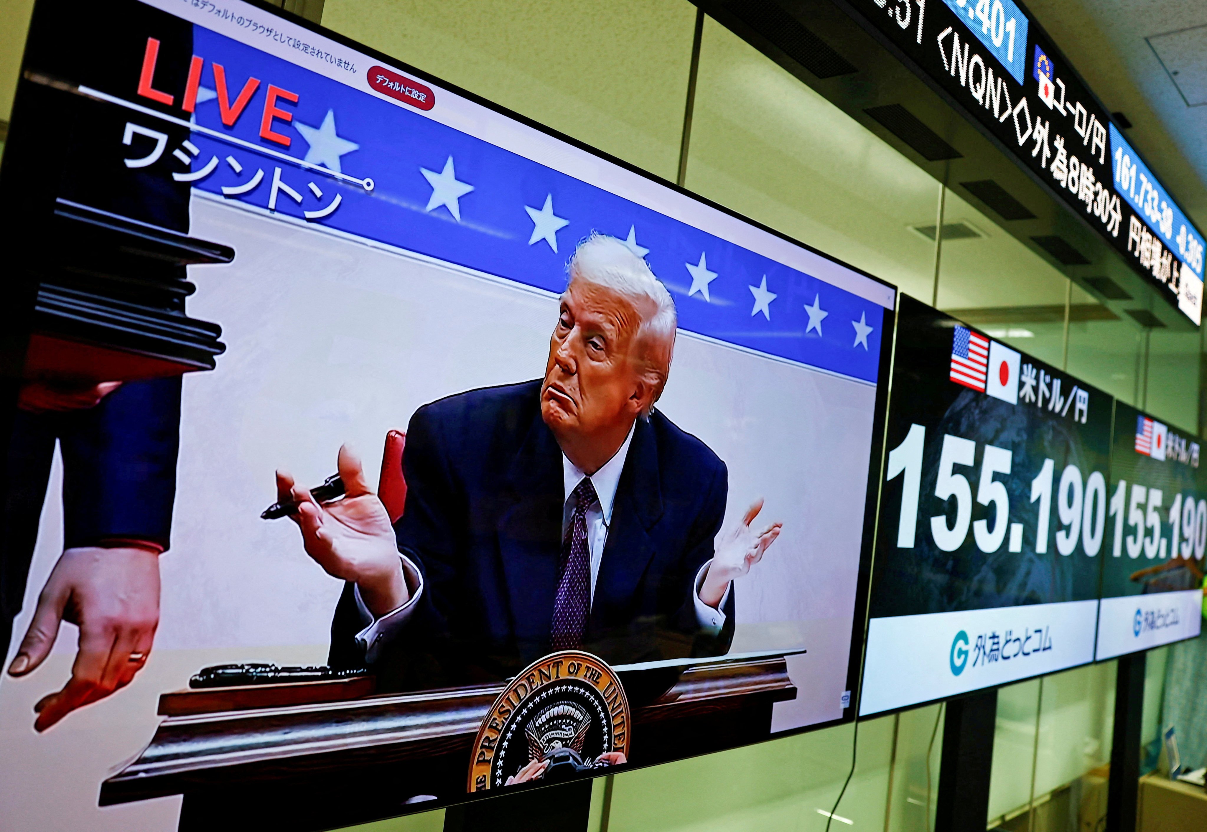 A screen broadcasting live footage shows US President Donald Trump gesturing while signing executive orders next to screens displaying the current Japanese yen exchange rate against the US dollar at a foreign exchange trading company in Tokyo, Japan,  on January 21. Photo: Reuters