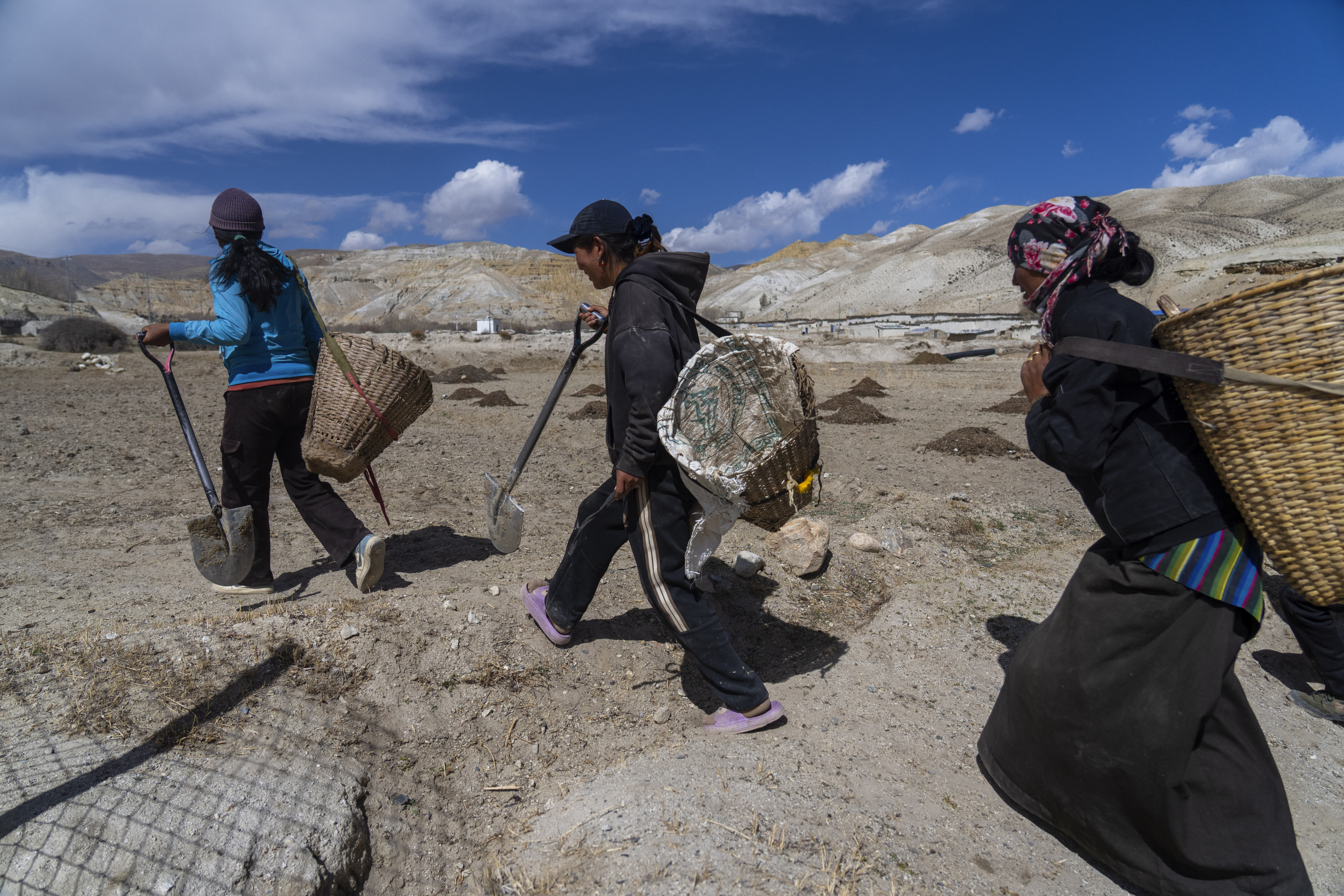 Villagers walk towards a field to plant apple trees in the newly relocated settlement of the abandoned Samjung village on April 18.  Photo: AP