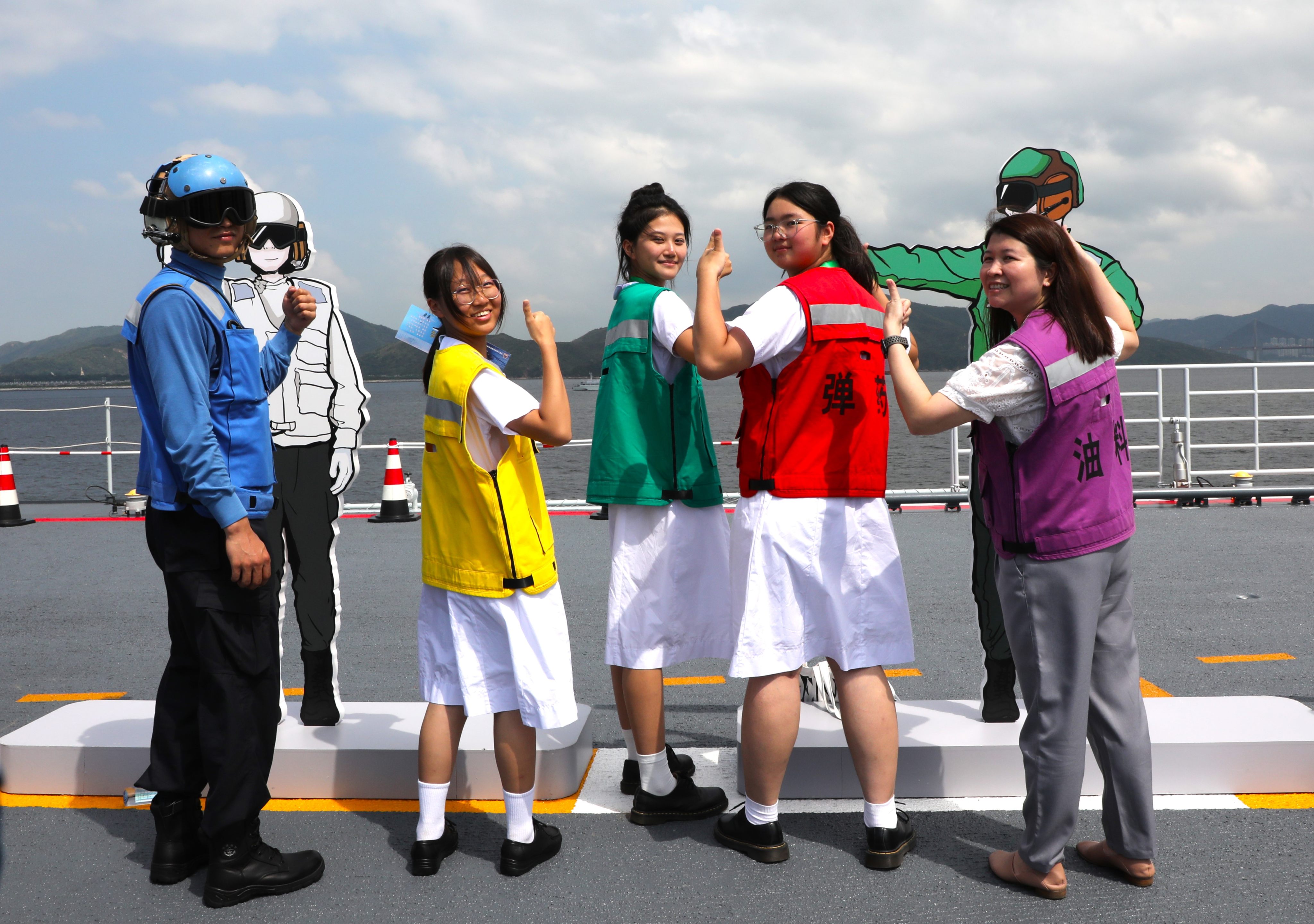 Visitors try on the coloured vests used by crew members on the deck of the Shandong. Photo: Xinhua