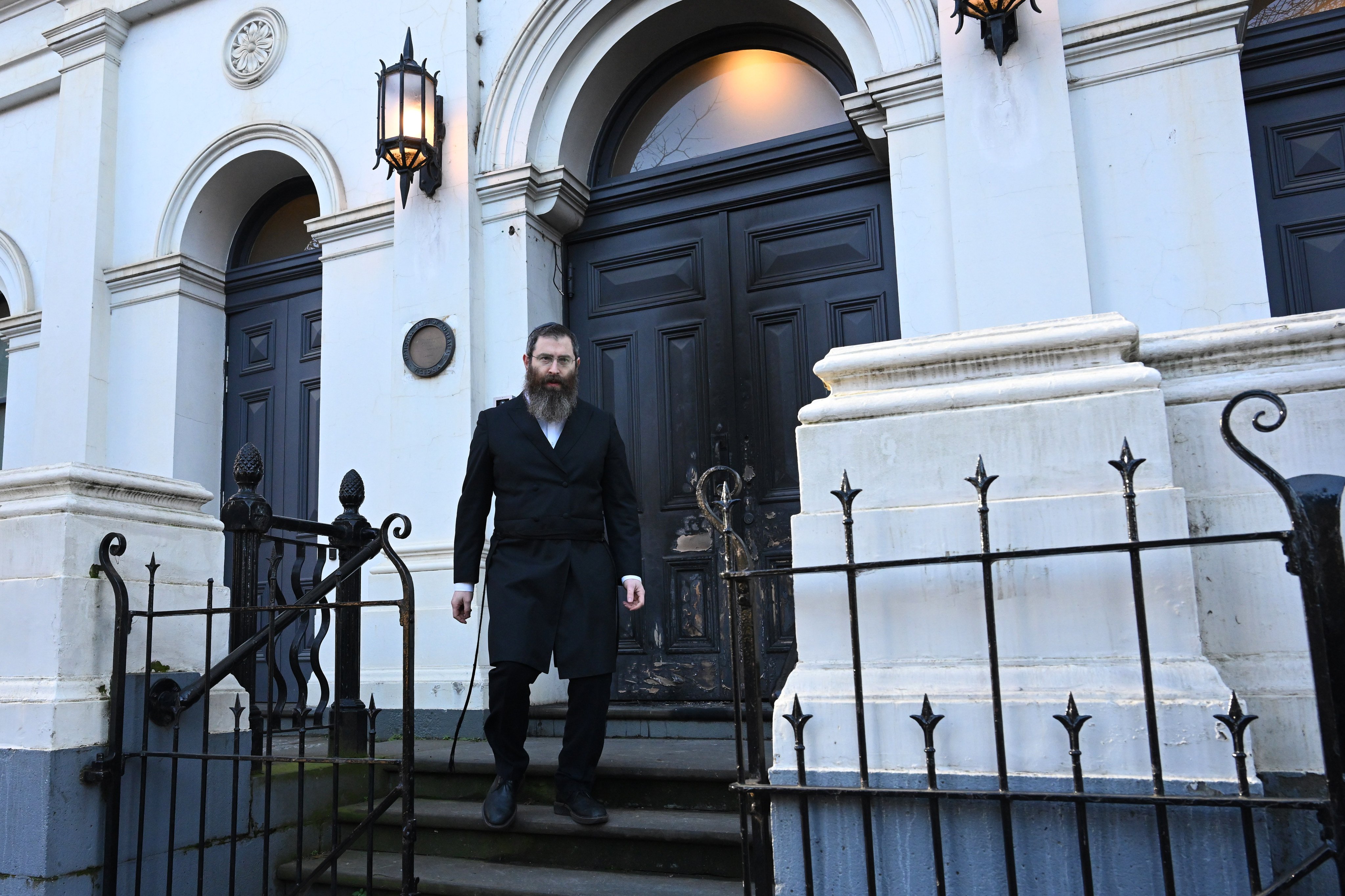 Rabbi Dovid Gutnick stands outside the damaged exterior of the East Melbourne Hebrew Congregation in Melbourne. Photo: AAP/dpa