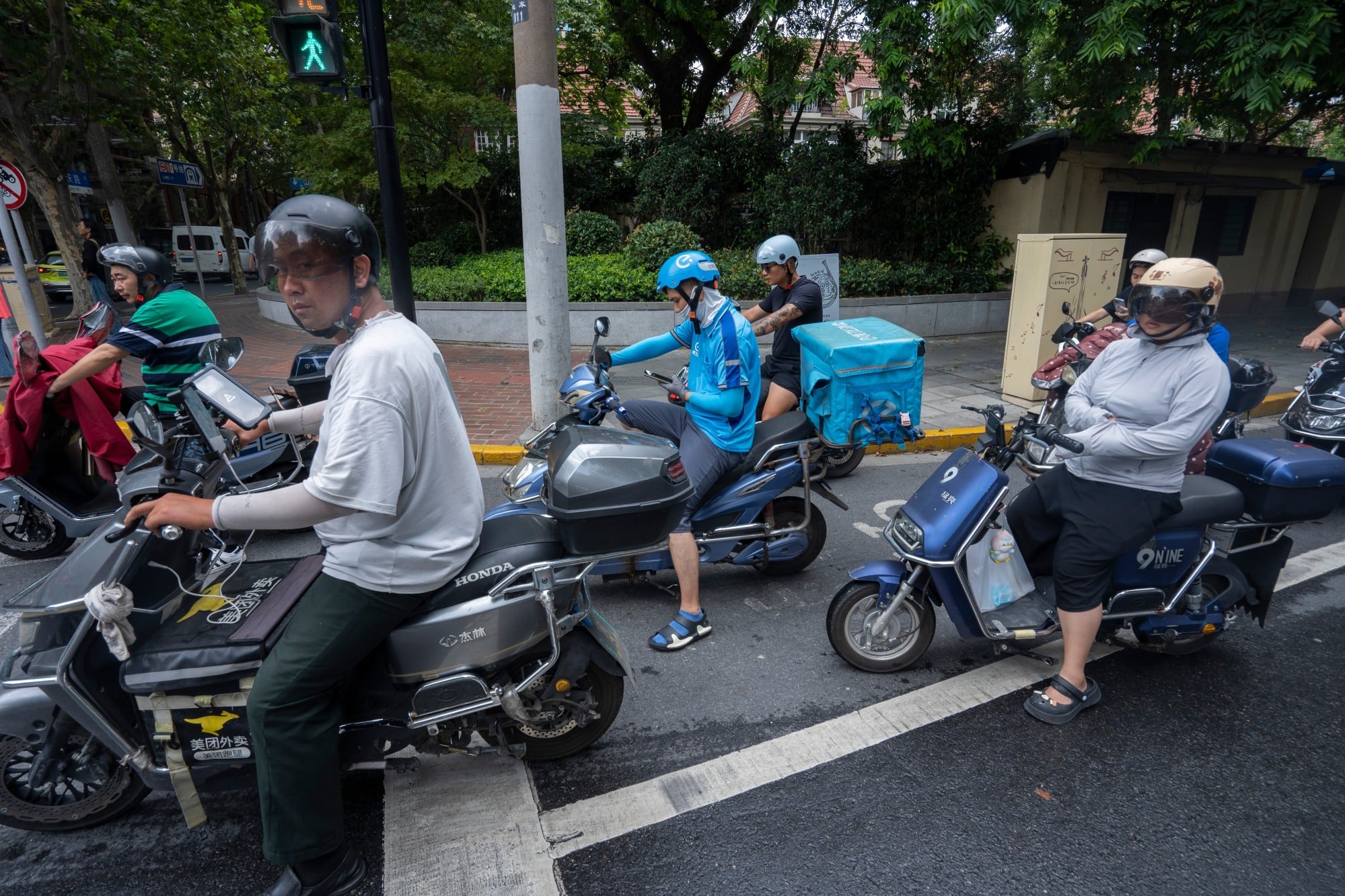 Meituan and Ele.me delivery workers are seen waiting at a traffic junction in Shanghai. Photo: Shutterstock