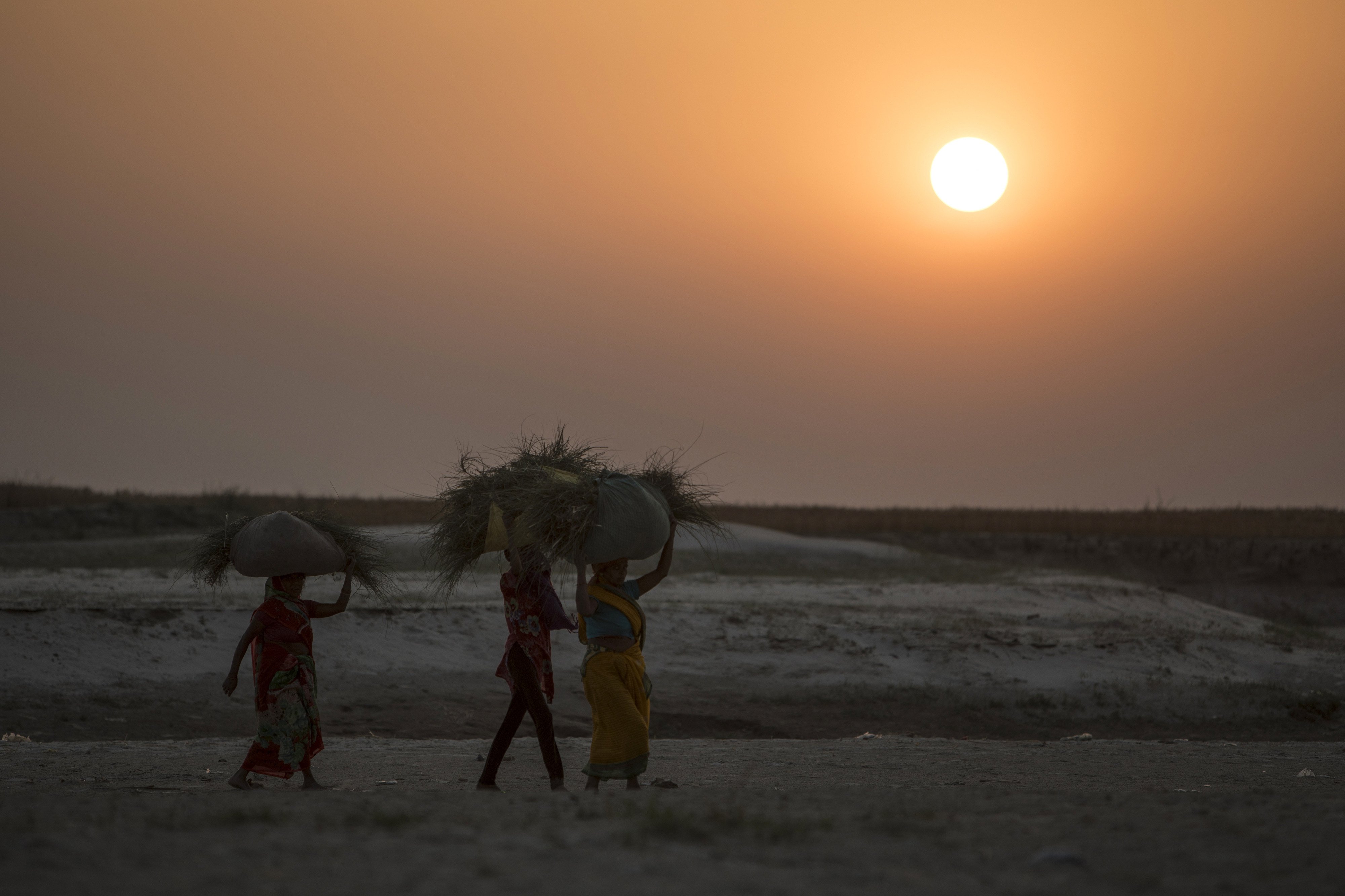 Indian farmers walk at sunset along the dry banks of a tributary of the river Ganges, in the Indian state of Bihar. Photo: AFP