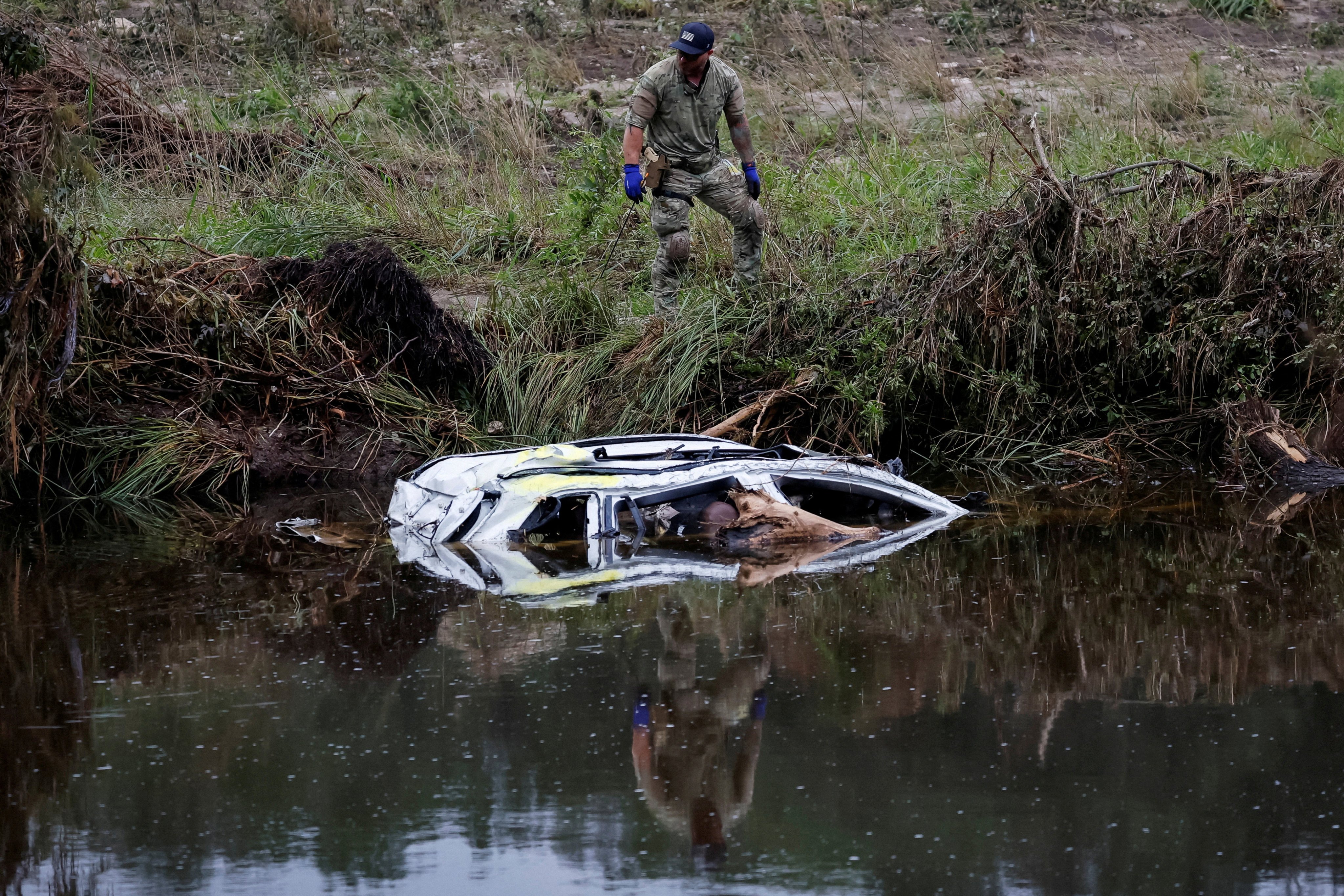 One of many rescuers continues the grim search for people swept away by torrents of water. Photo: Reuters