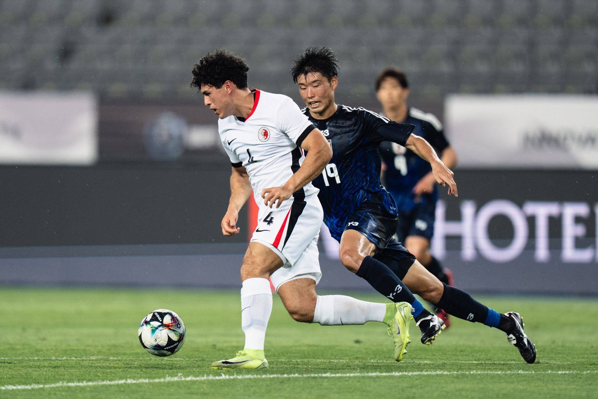 Hong Kong’s Leon Jones tries to drive clear of Japan forward Yuki Kakita. Photo: HKFA