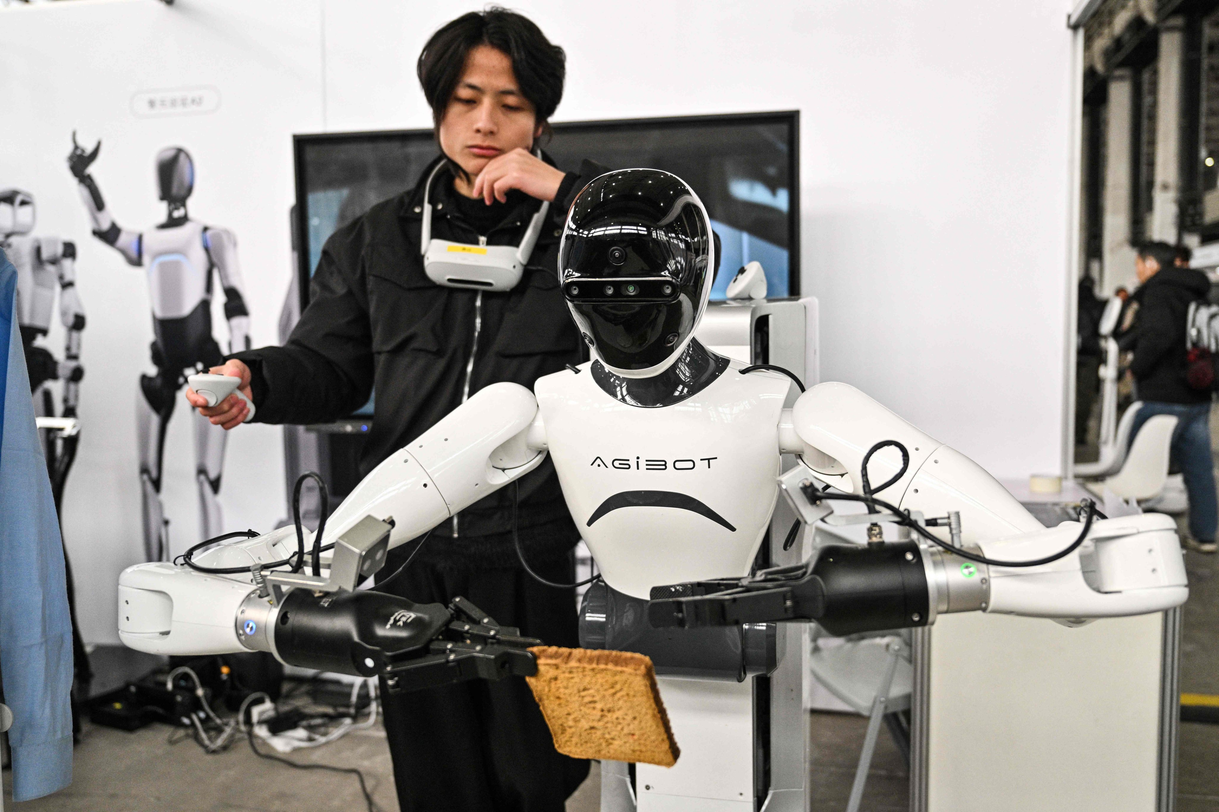 A man controls an AgiBot robot during an event organised by the Shanghai AI Industry Association, in Shanghai, February 21, 2025. Photo: AFP