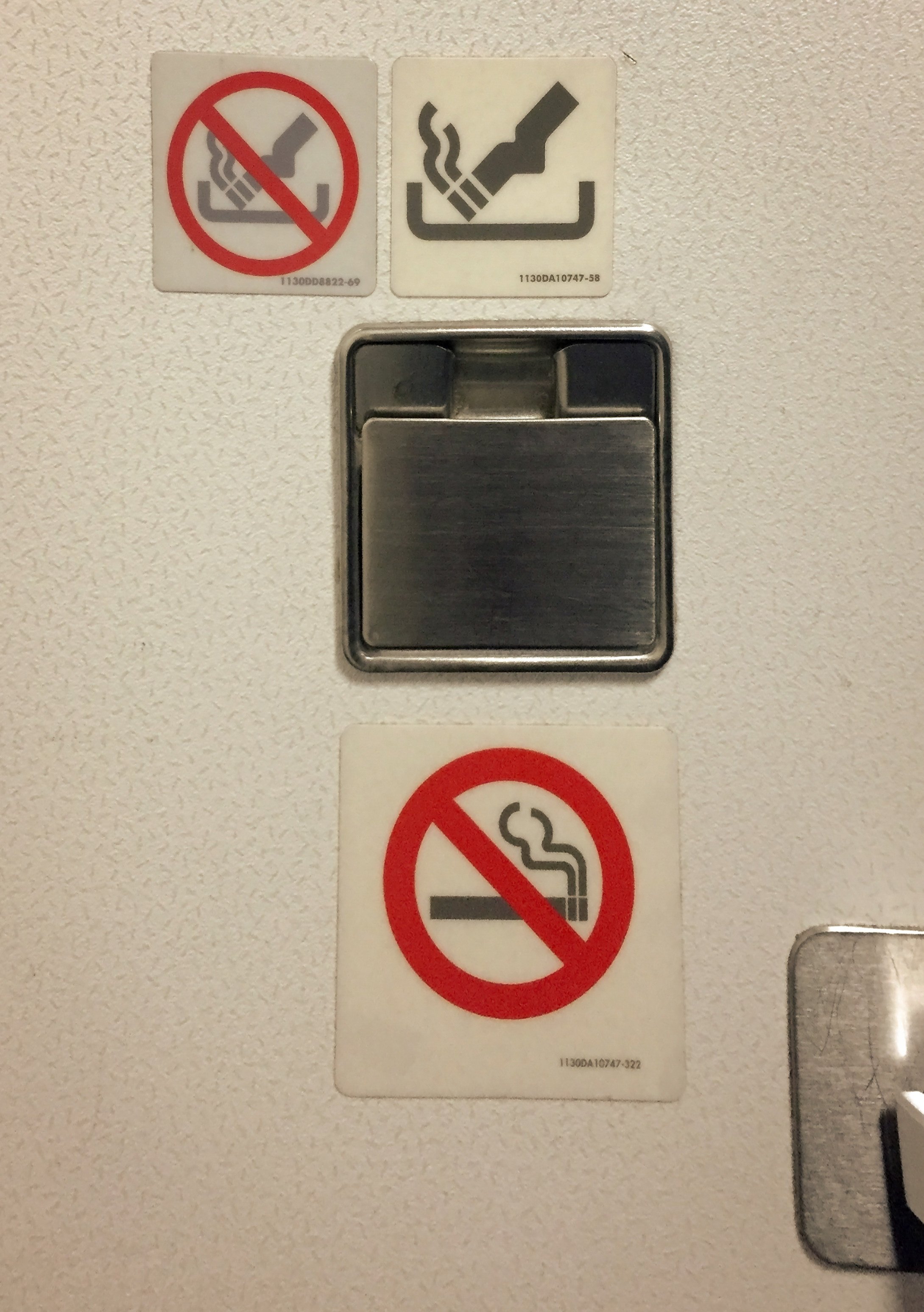 Yes, here is an ashtray but do not use it. Competing notices send mixed messages in an aeroplane lavatory. Photo: Shutterstock